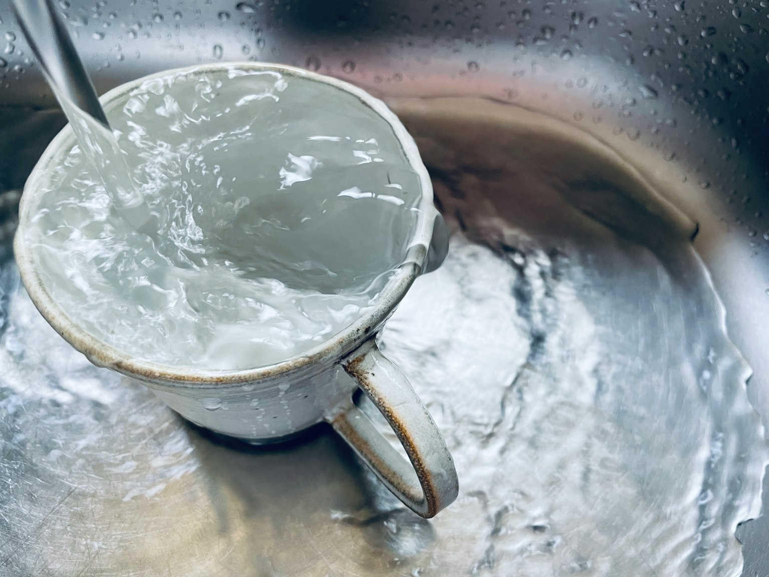 Una taza de cerámica blanca llena de agua colocada en un fregadero