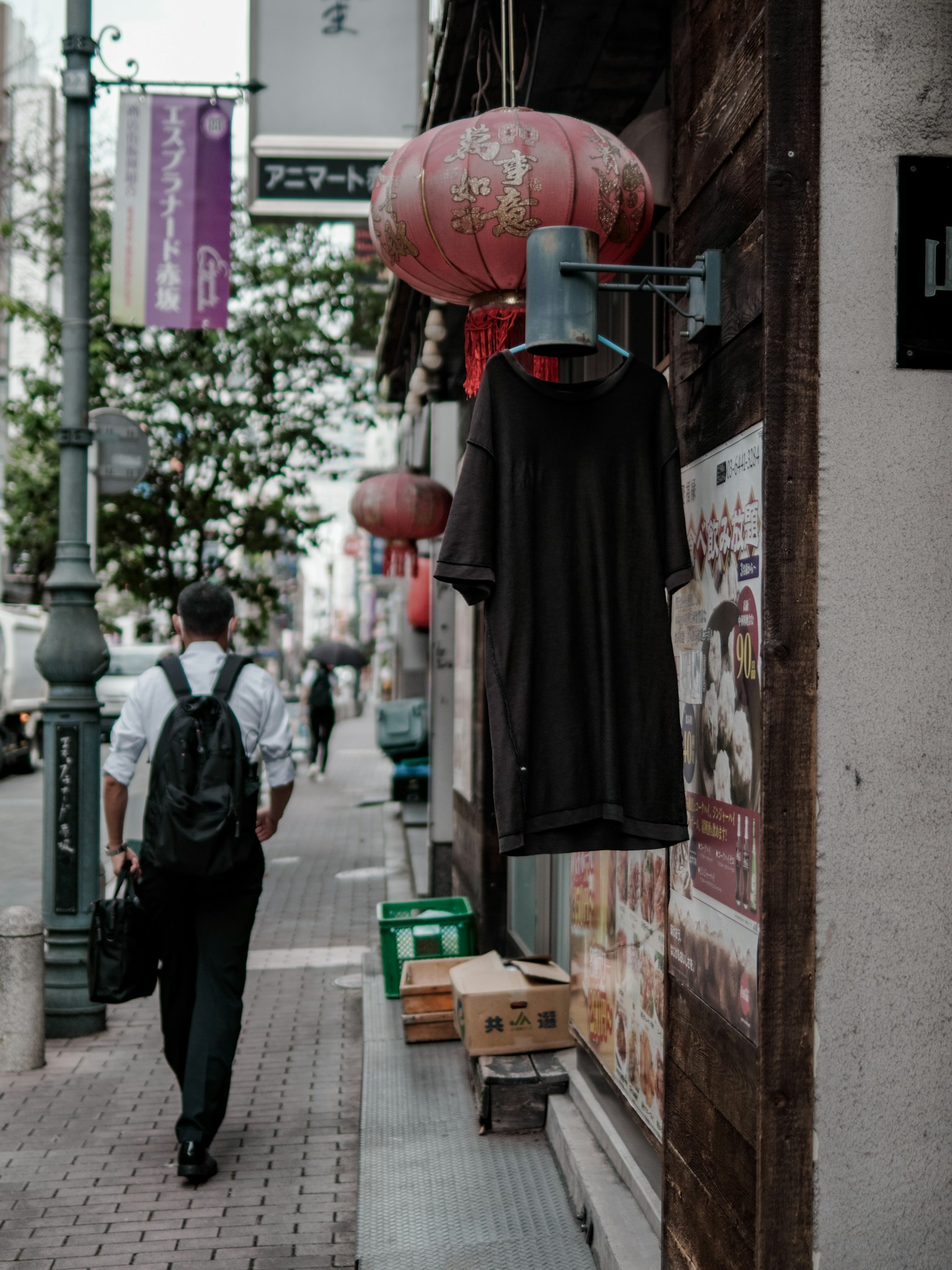 一个人走在街上,旁边有悬挂的衣服和灯笼