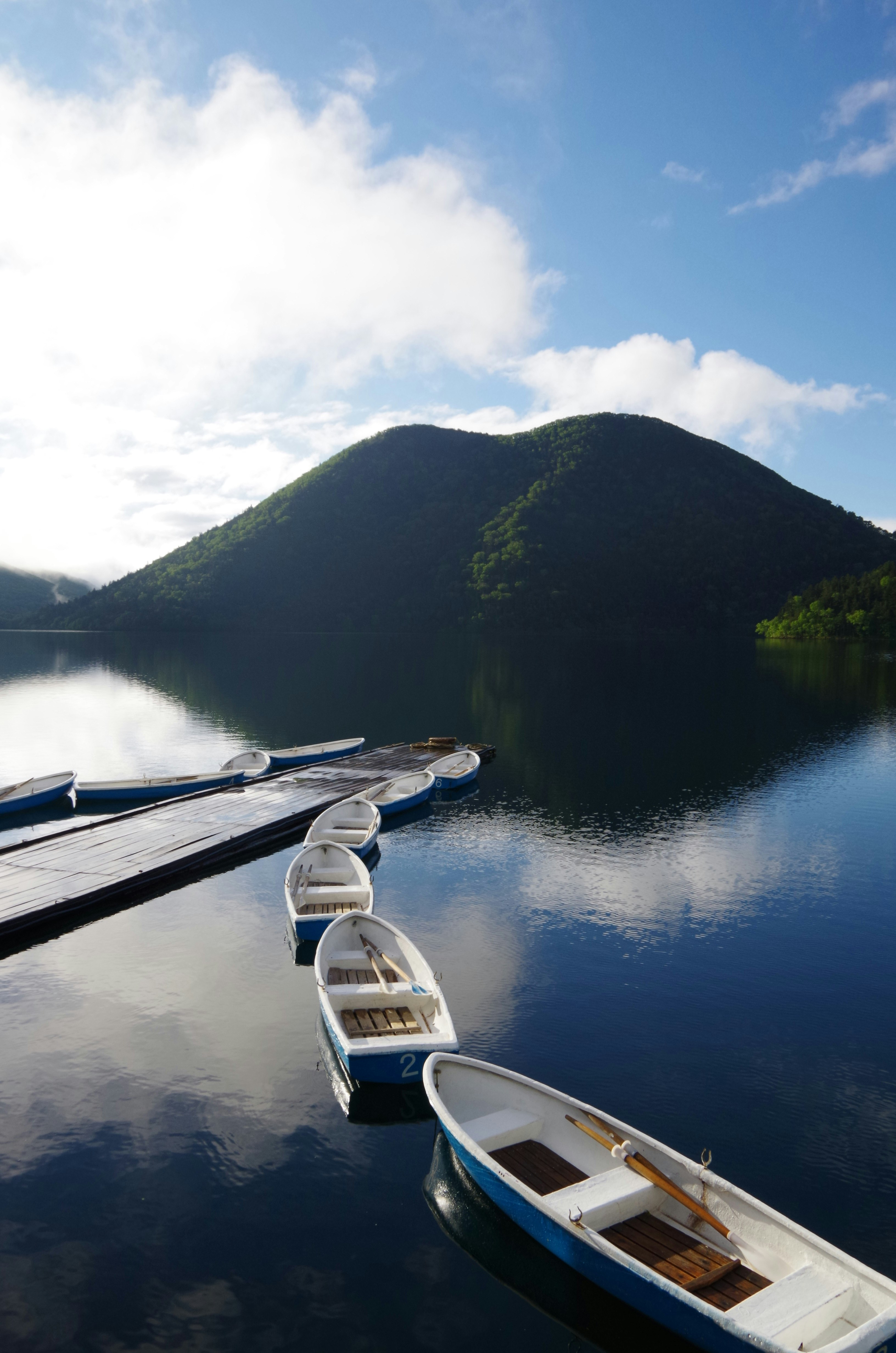 然別湖の静かな水面とボート、山並みの風景