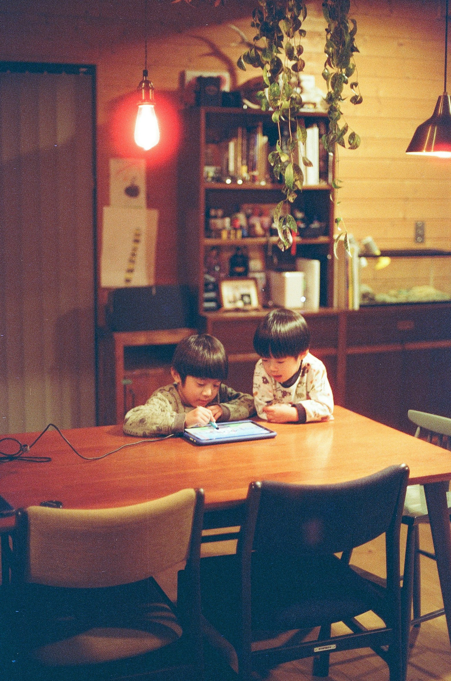 二人の子供がテーブルでタブレットを見ている温かい室内のシーン