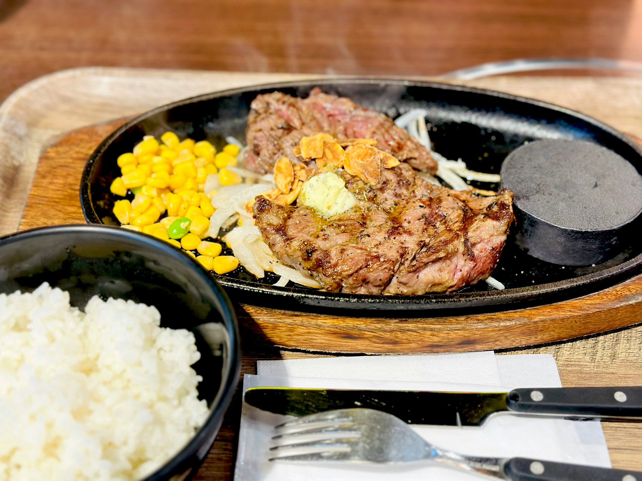 鉄板で焼いたステーキと付け合わせ、木製トレイの食卓