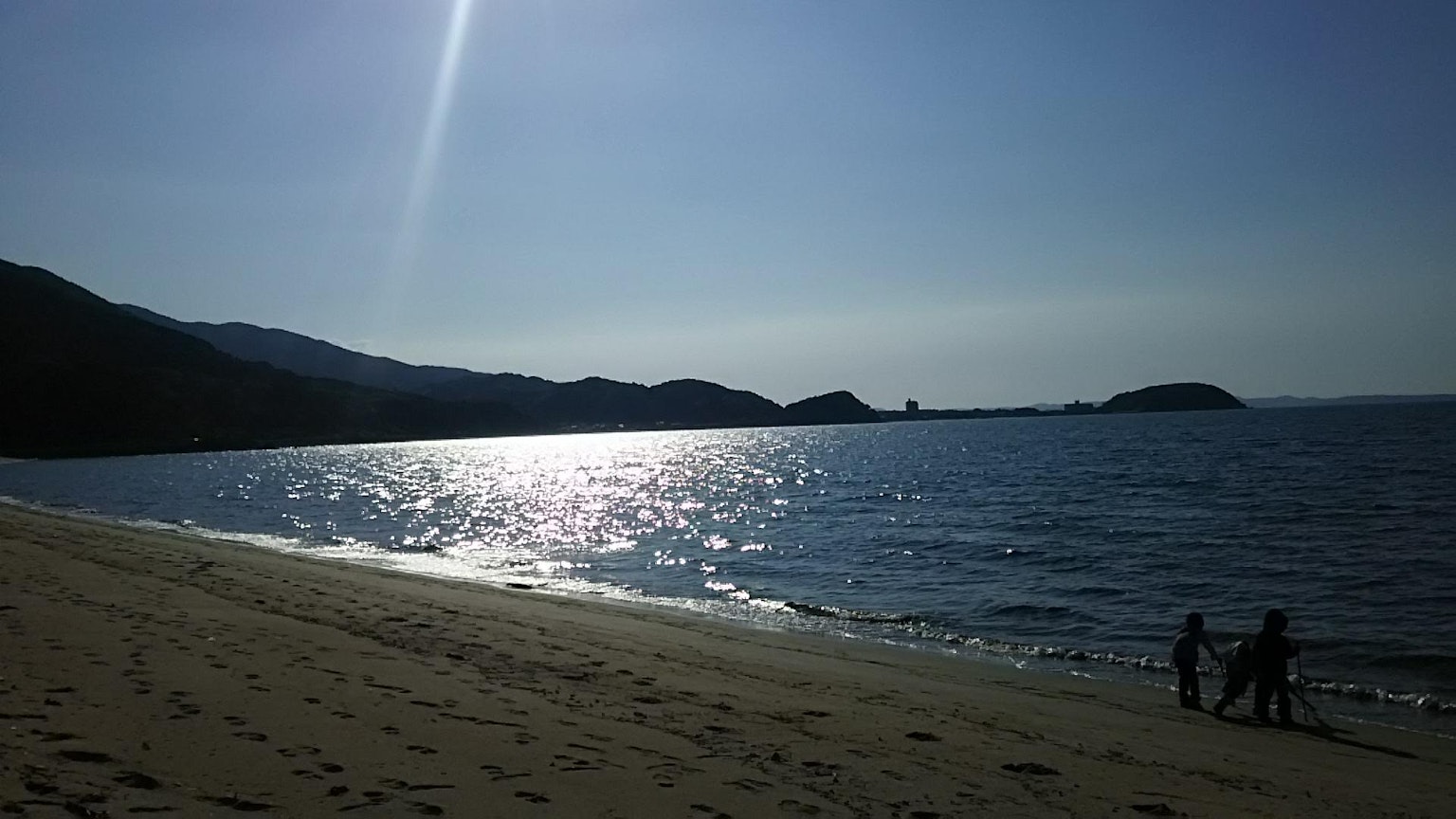宁静的海滩场景，阳光在水面上反射