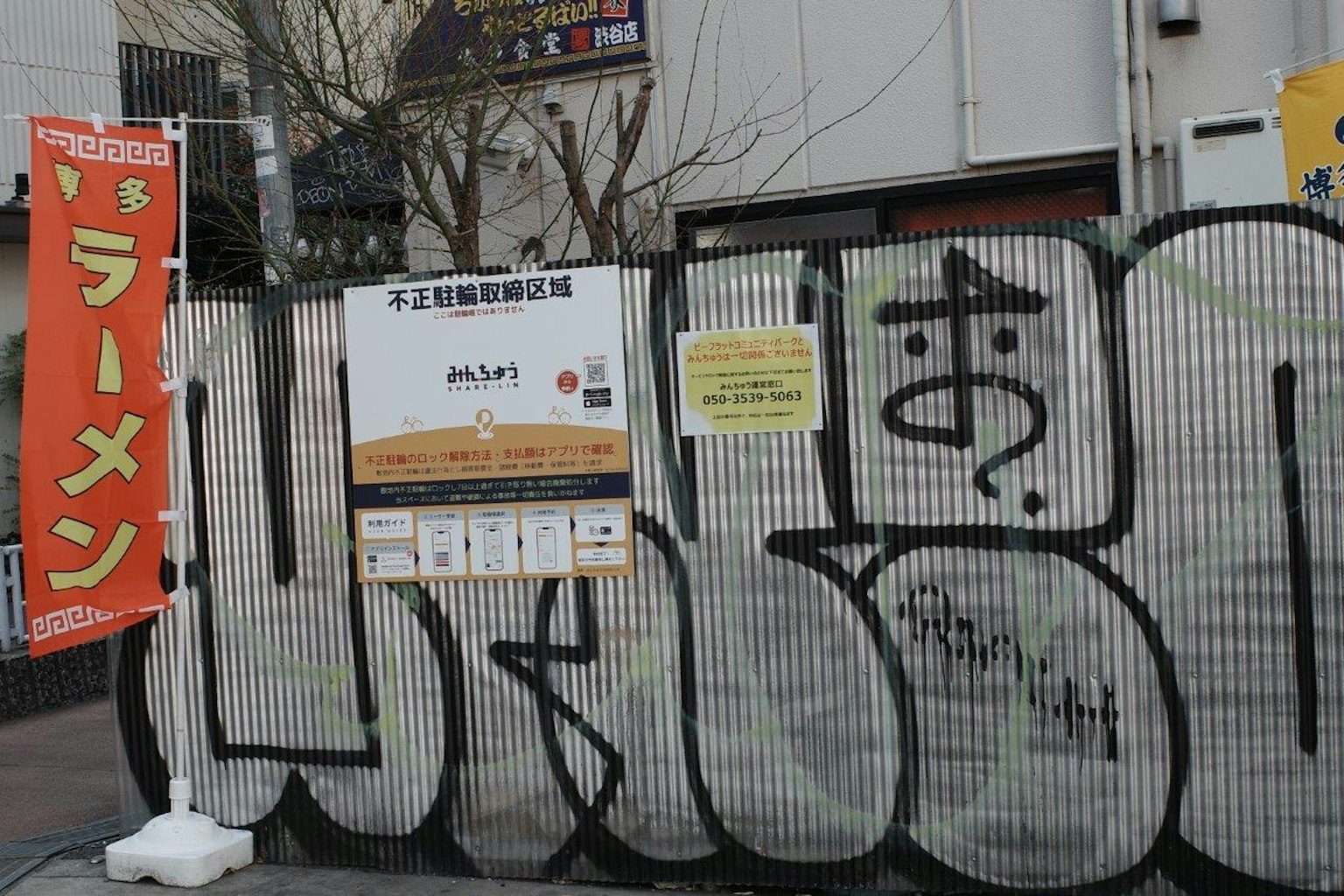 拉麵店招牌和塗鴉覆蓋的圍欄的場景