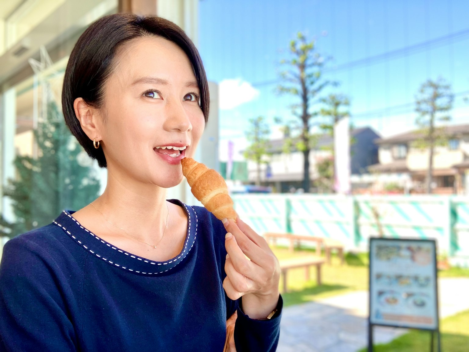 一位女性正在享用冰淇淋，背景中有綠色的樹木