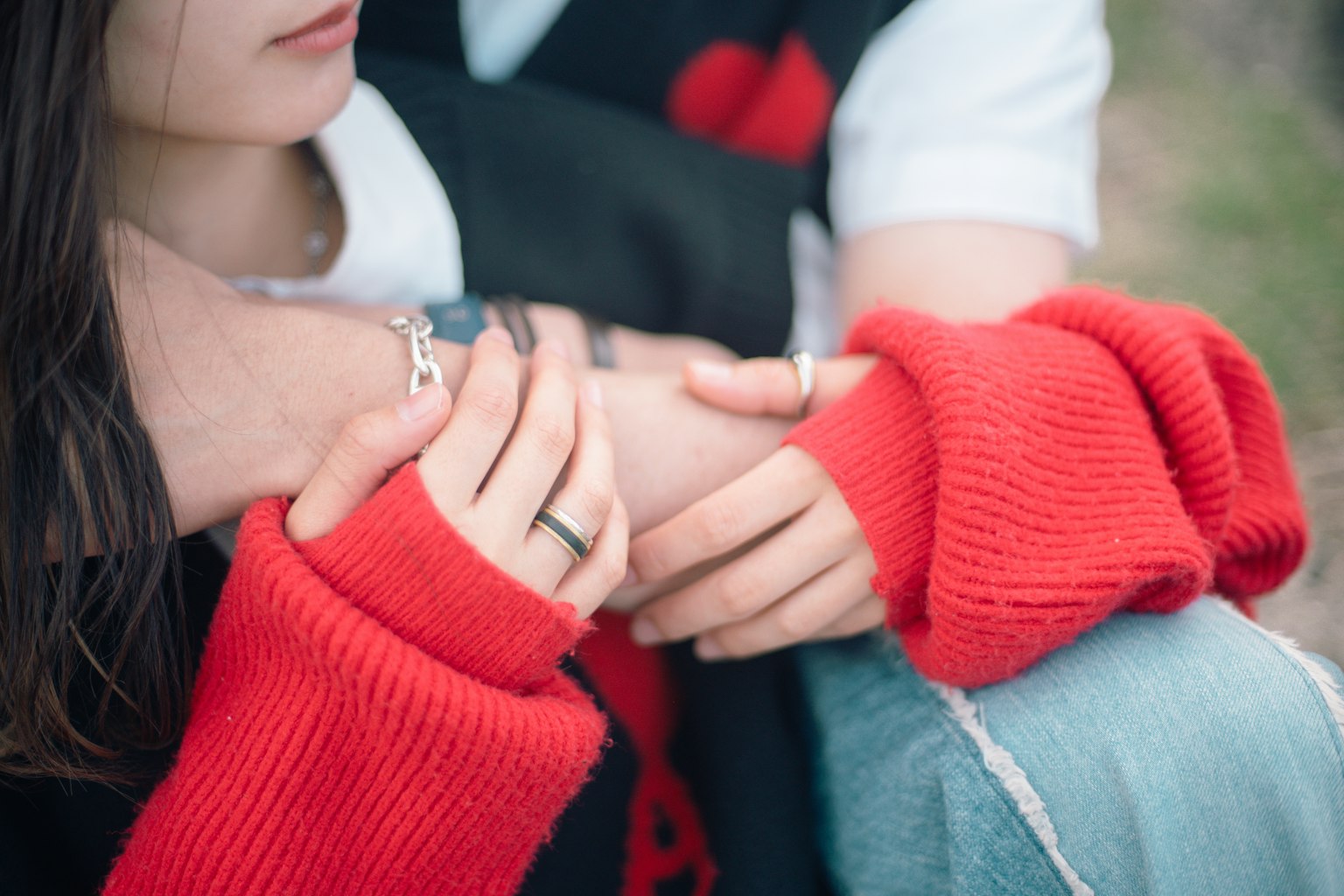 Manos entrelazadas de una pareja con un suéter rojo