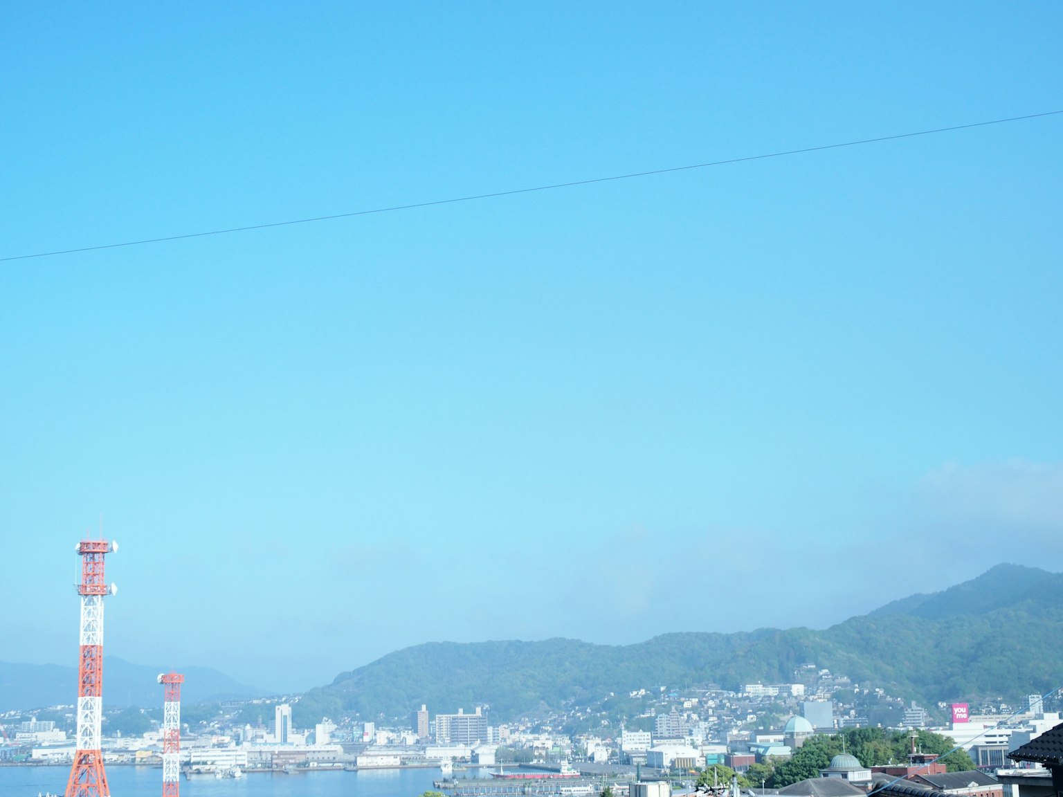 ทิวทัศน์เมืองชายฝั่งที่มีท้องฟ้าสีฟ้าและภูเขา