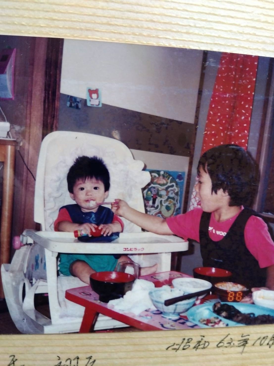 Escena de comida en interior con un niño de rojo y una trona