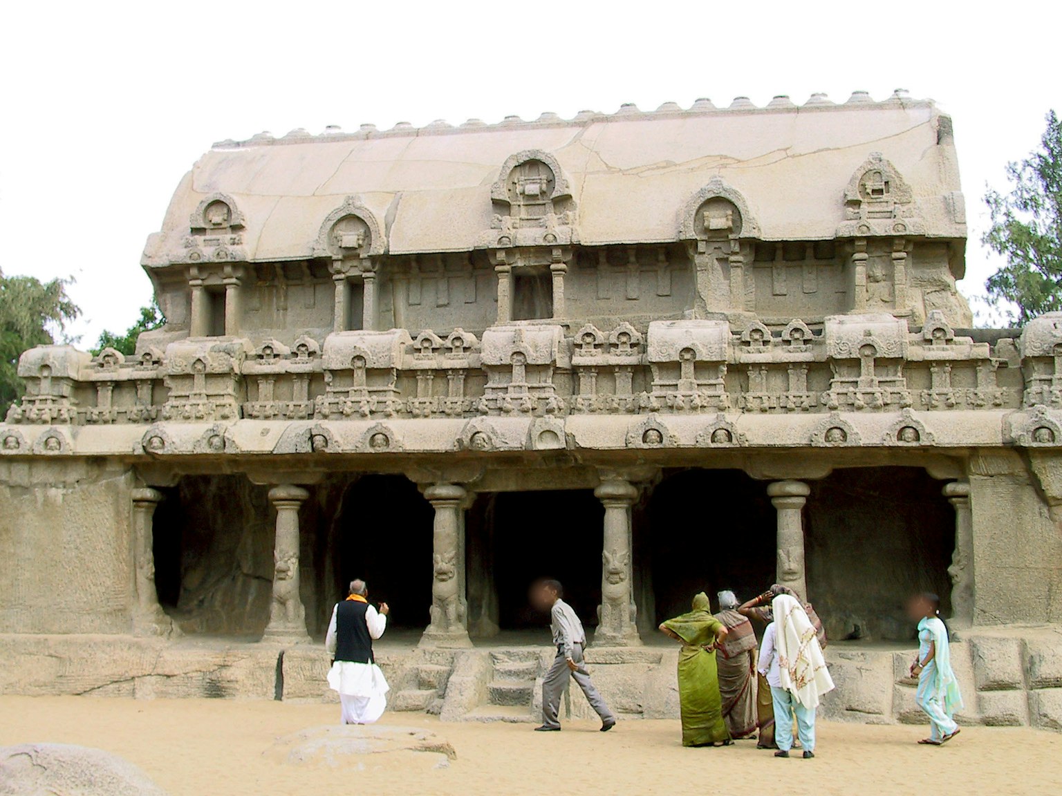 Ancienne structure en pierre avec des touristes à proximité