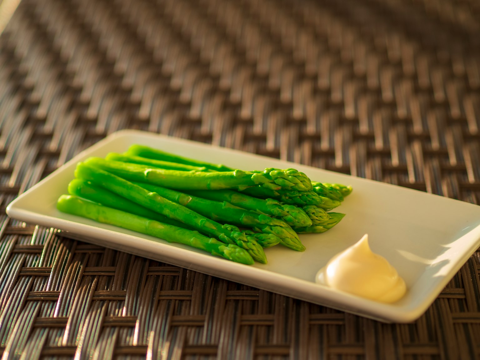 Espárragos verdes frescos en un plato blanco con salsa cremosa