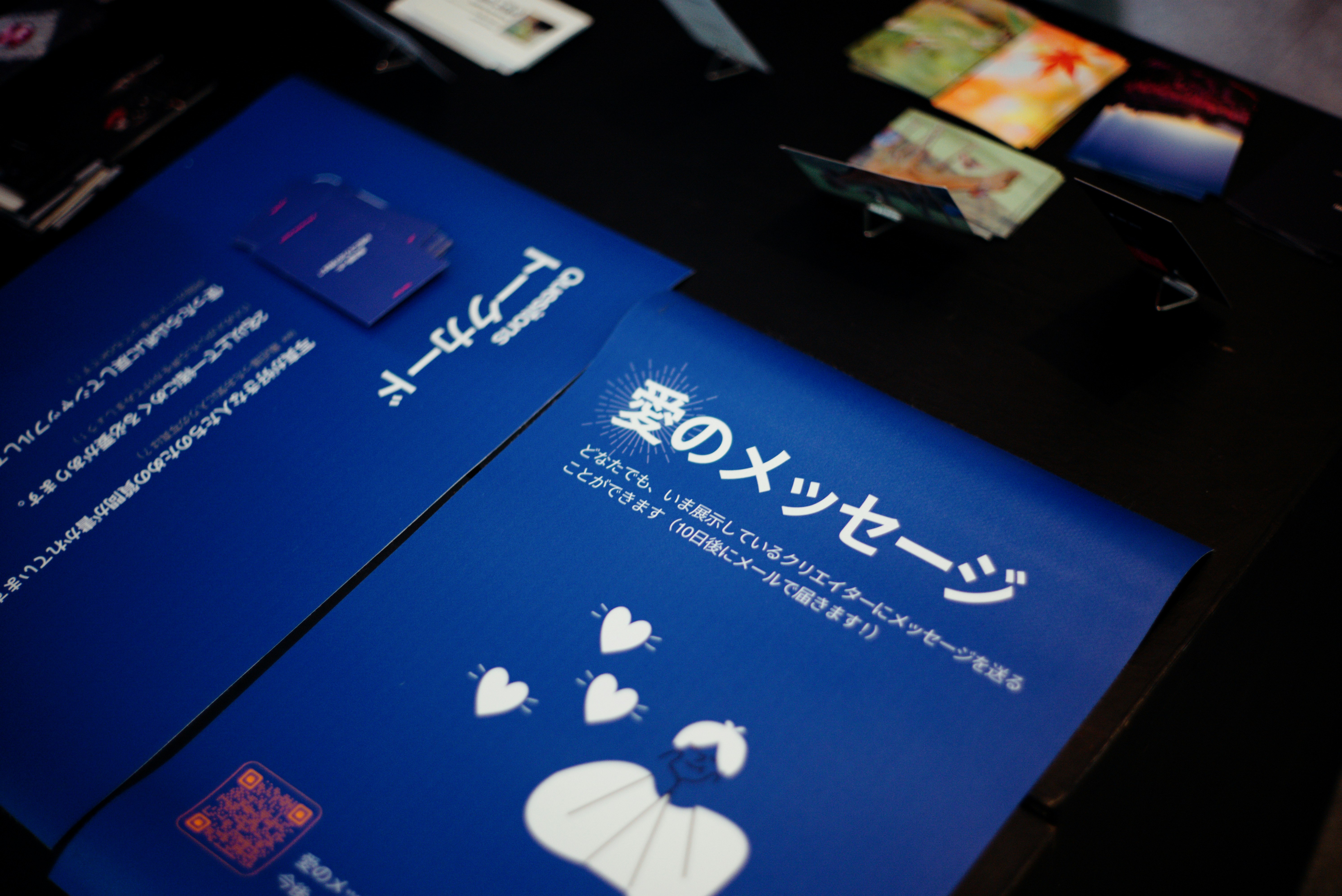 青い冊子とパンフレットが並ぶ展示テーブル