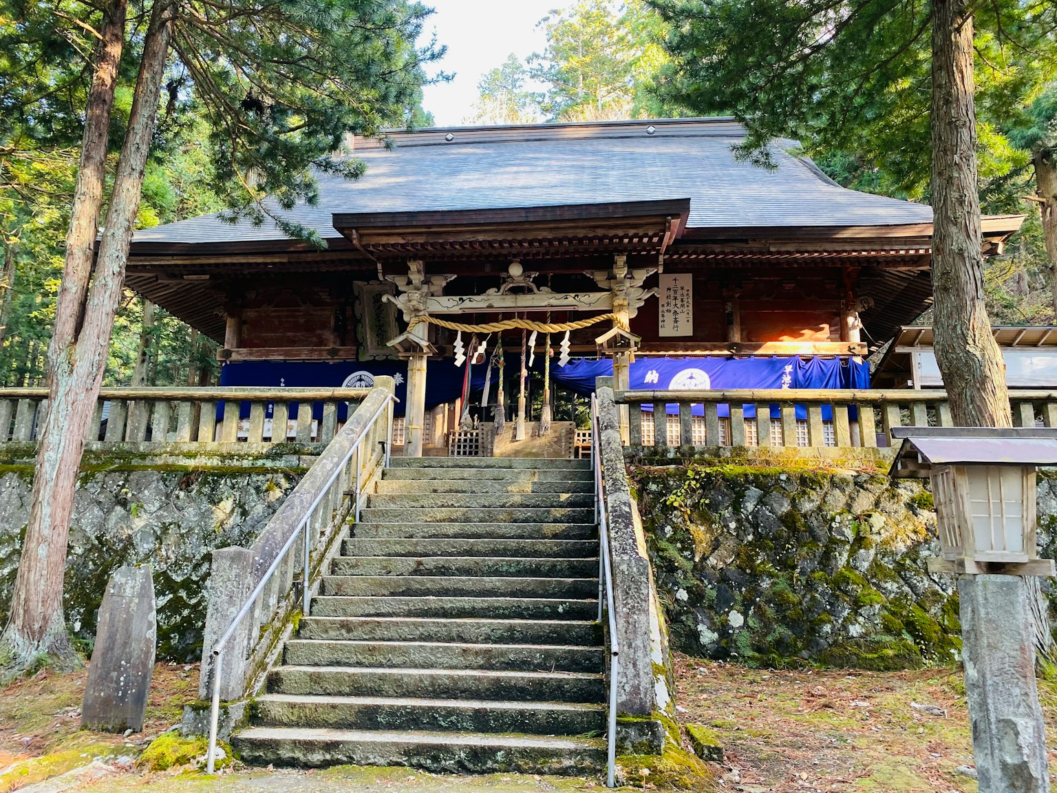 Edificio del santuario in legno in cima a gradini di pietra circondato da foresta