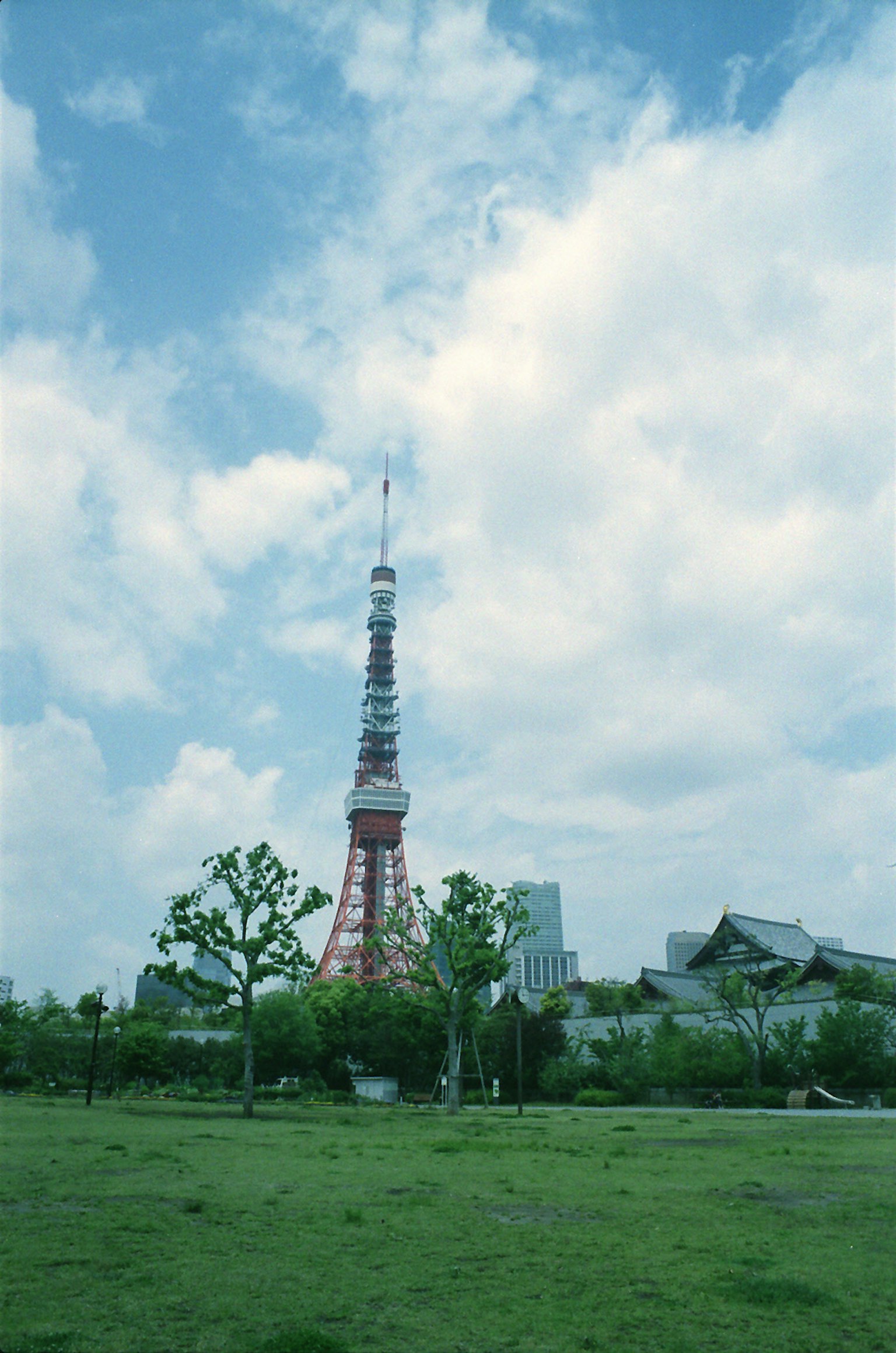 Tokyo Tower against a blue sky with a green park in the foreground
