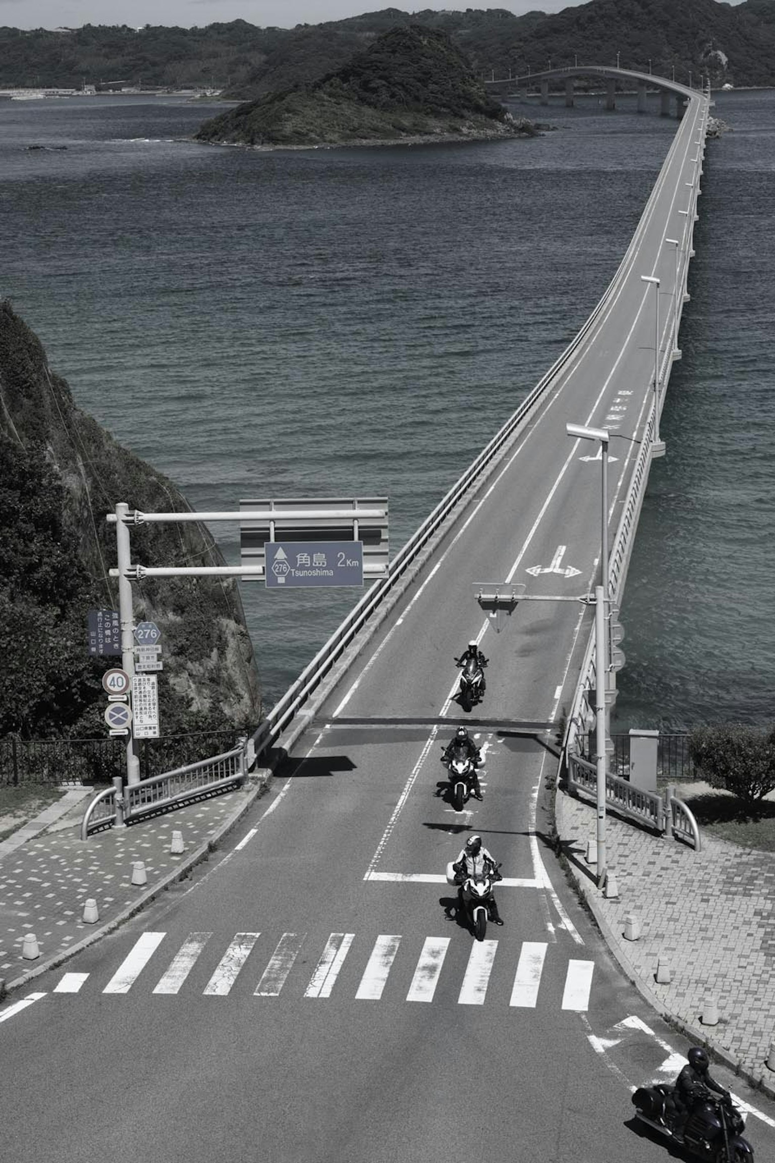 Sekelompok sepeda motor melintasi jembatan panjang di atas laut