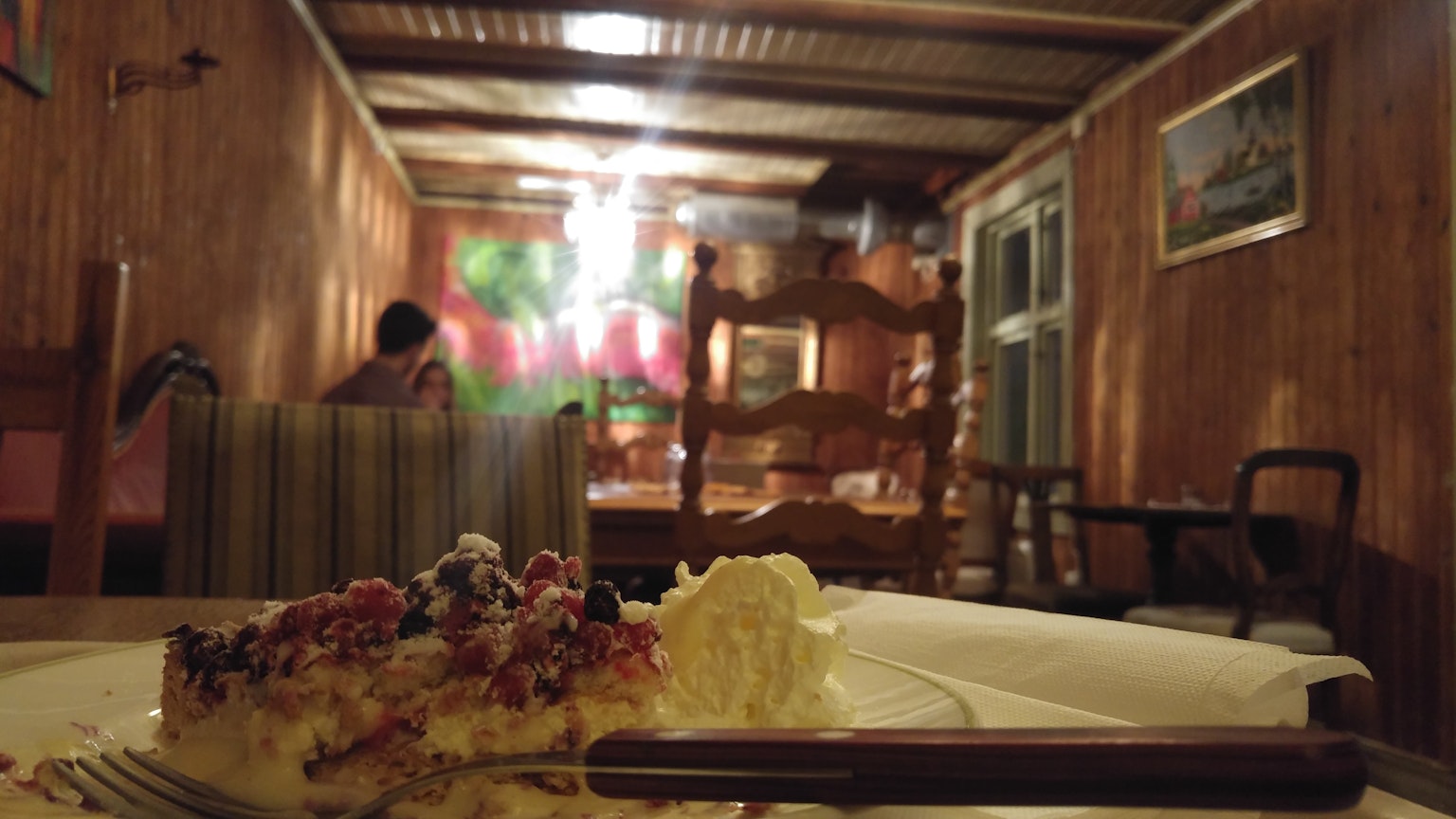 Assiette de dessert dans un restaurant à l'intérieur en bois avec une personne assise en arrière-plan