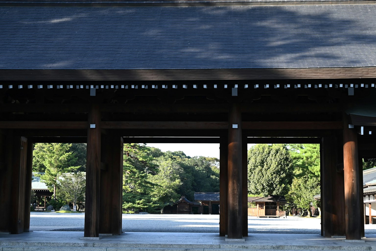 Grande porte en bois avec vue sur une verdure luxuriante à l'entrée d'un sanctuaire