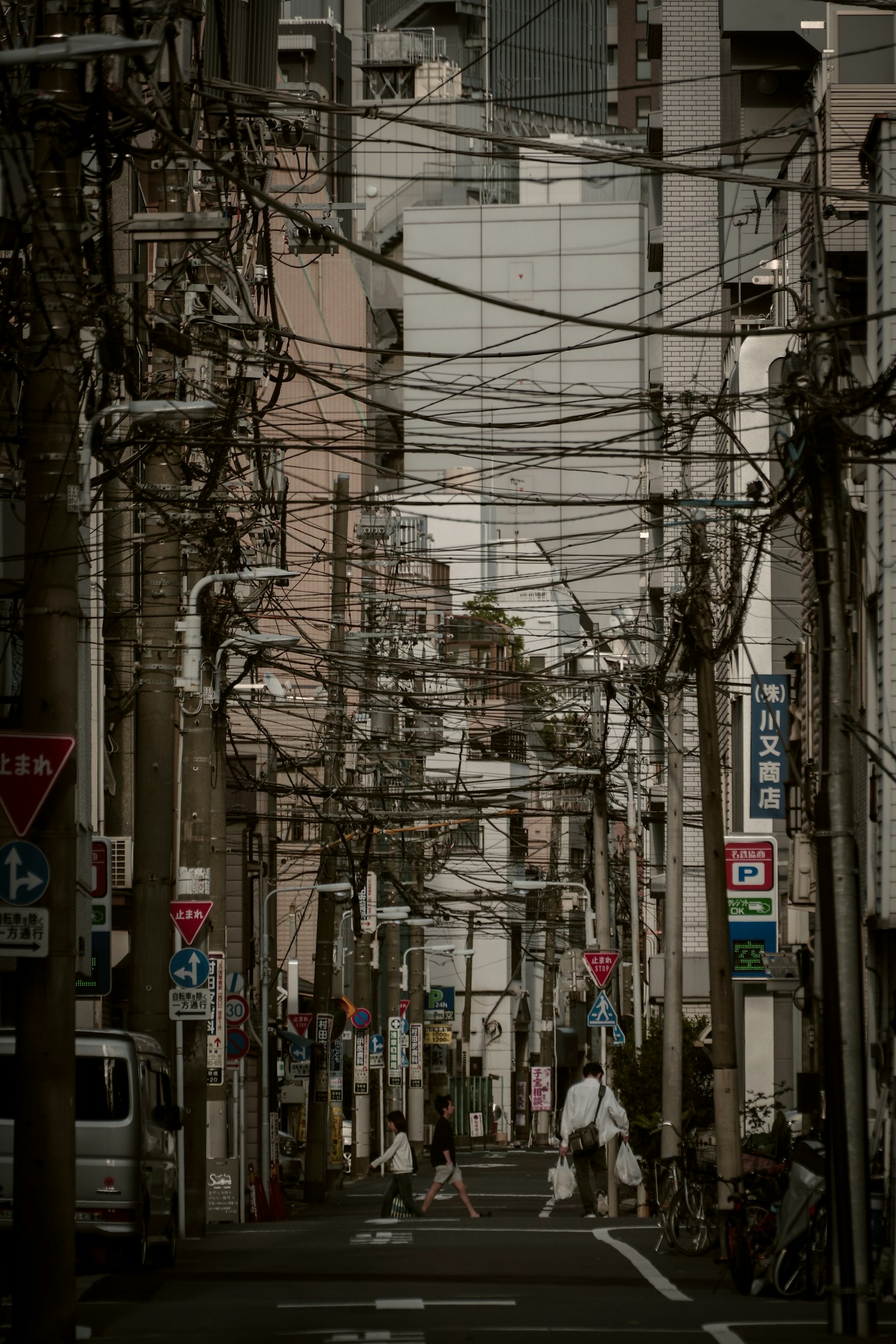 Callejón estrecho con líneas eléctricas y edificios Personas caminando