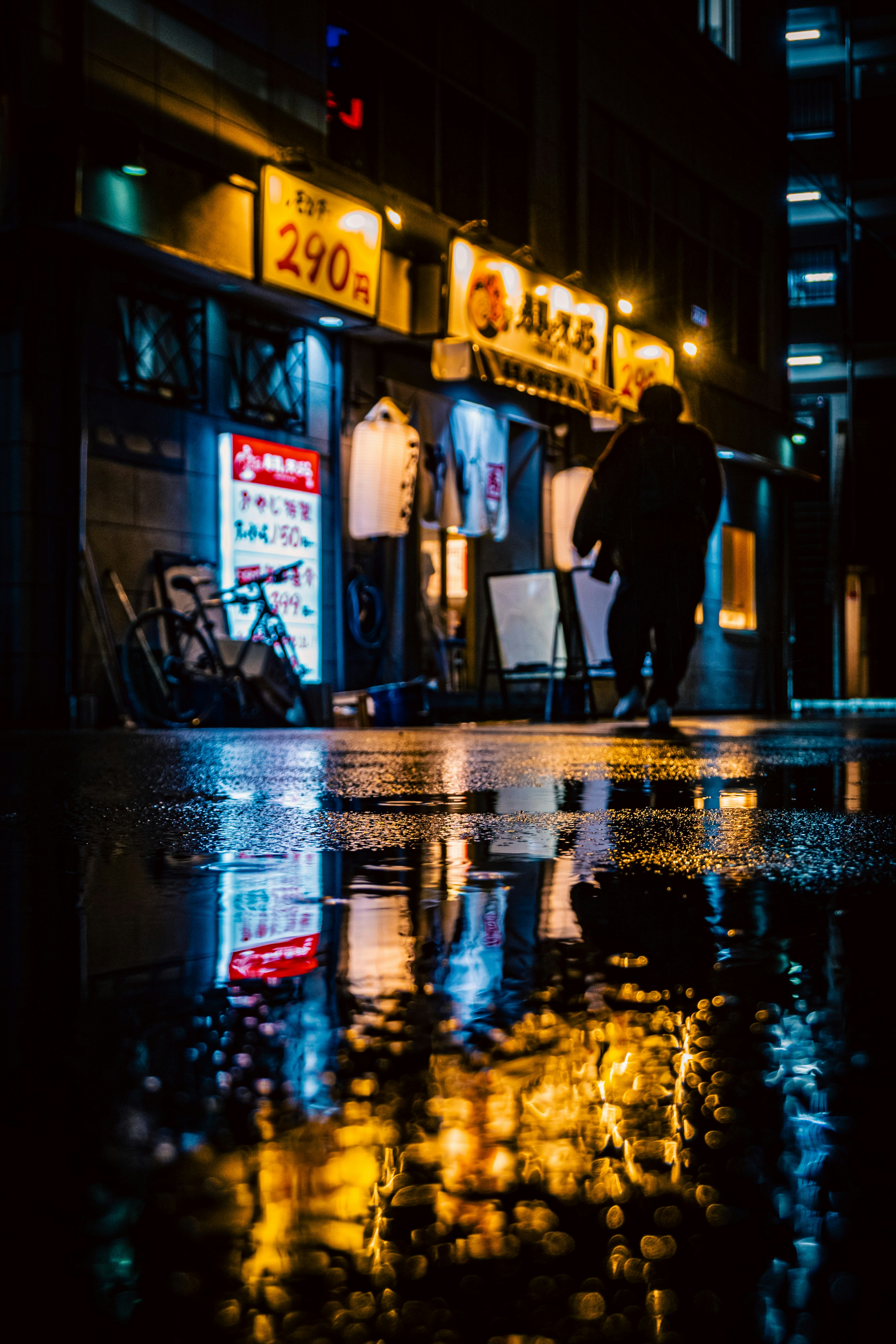 雨上がりの路地でネオンが反射する夜の商店街の軒先