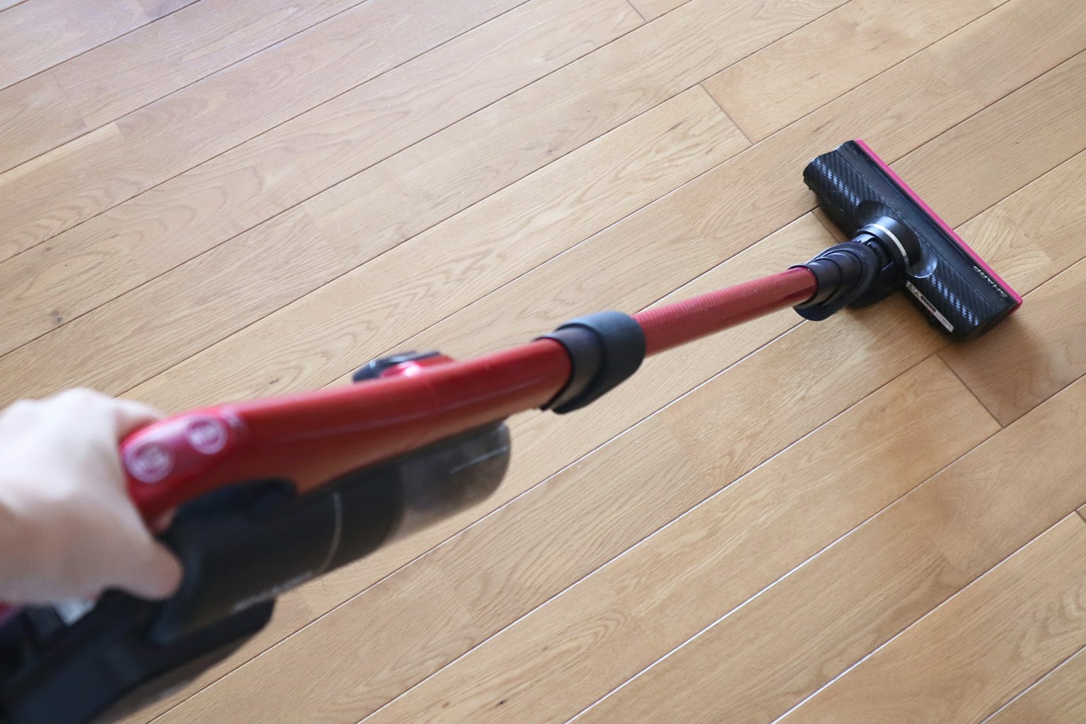 Un aspirateur à main rouge utilisé sur un sol en bois
