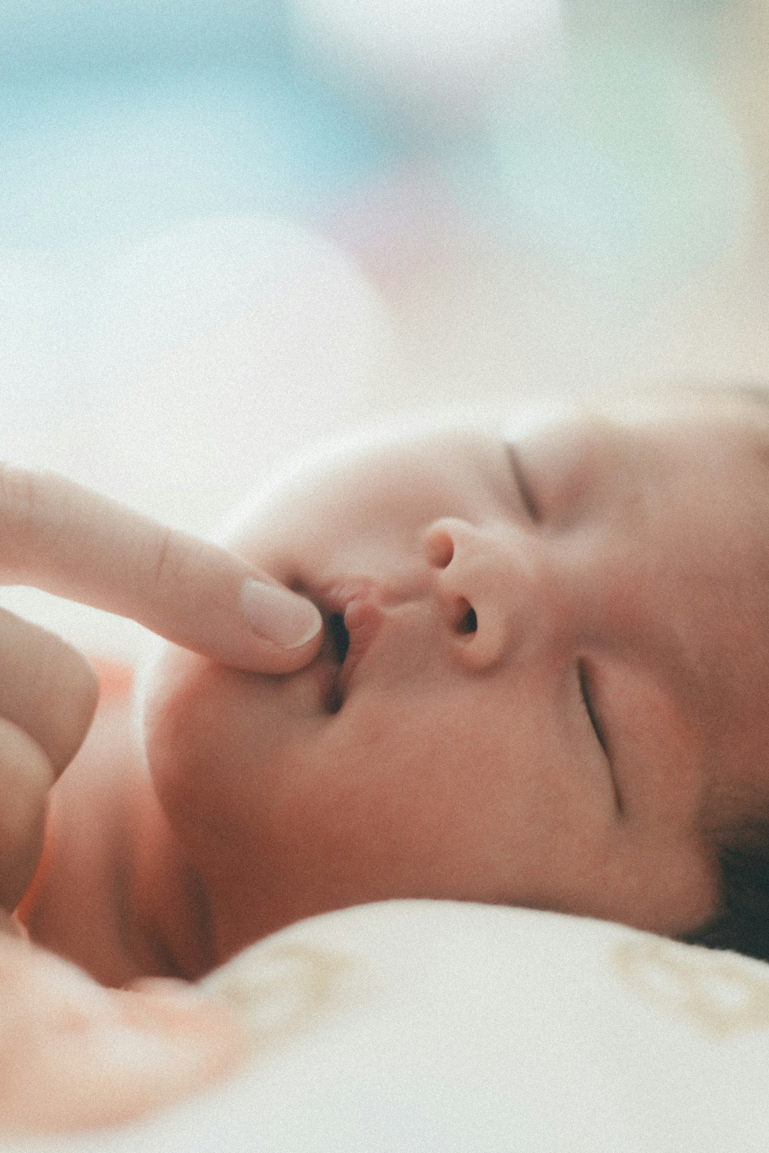 Bayi yang tidur dengan jari menyentuh mulutnya dengan lembut