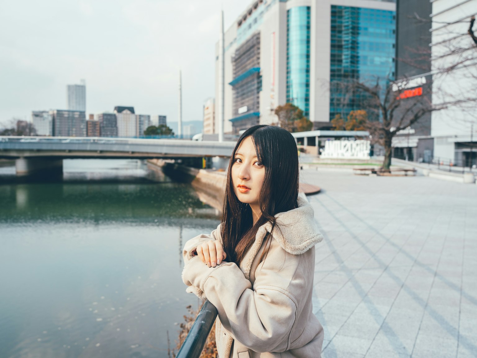河边站着的女性与现代建筑背景