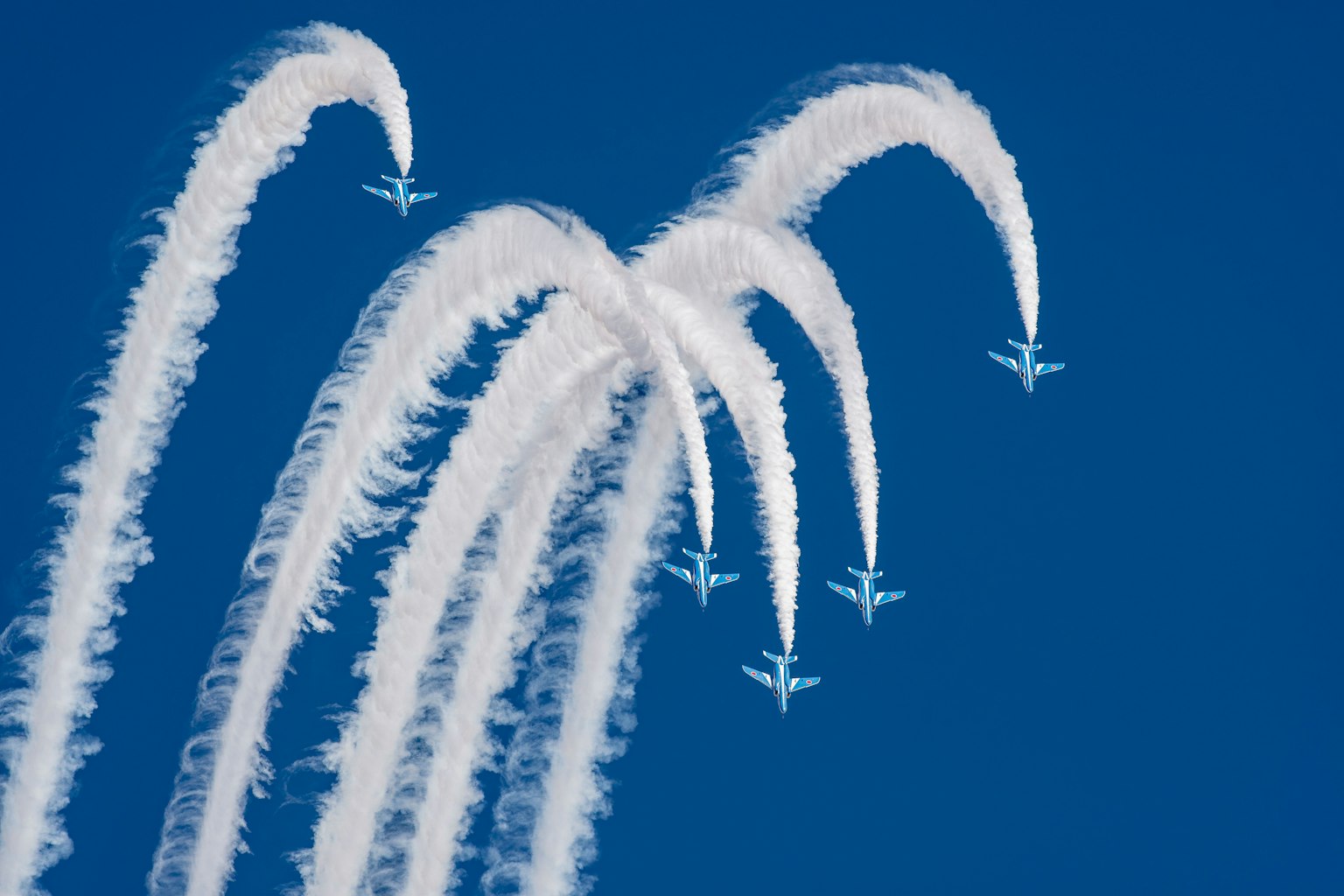Avions créant des arcs de fumée blanche dans un ciel bleu