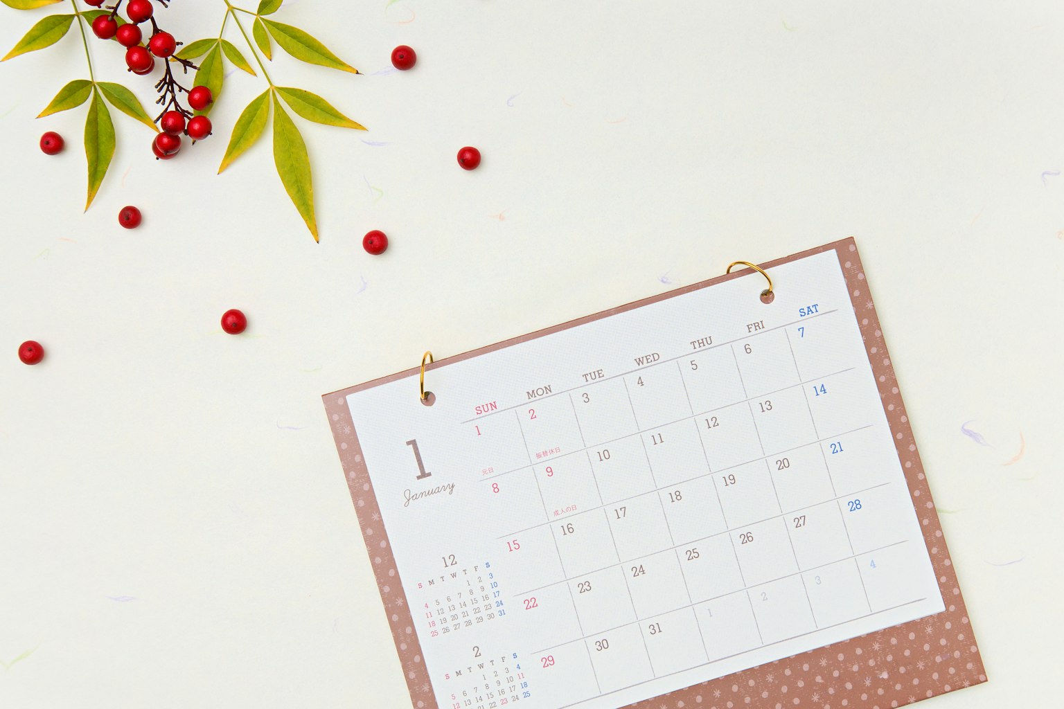 Calendario con bayas rojas y hojas verdes sobre un fondo claro
