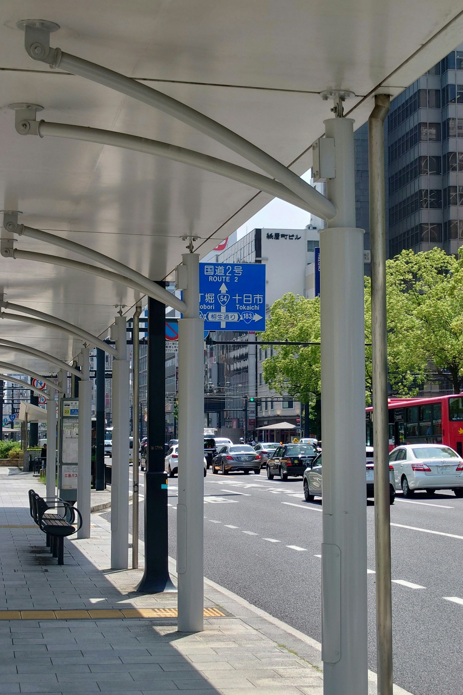 Arrêt de bus urbain avec scène de circulation panneau bleu arbres verts véhicules passant
