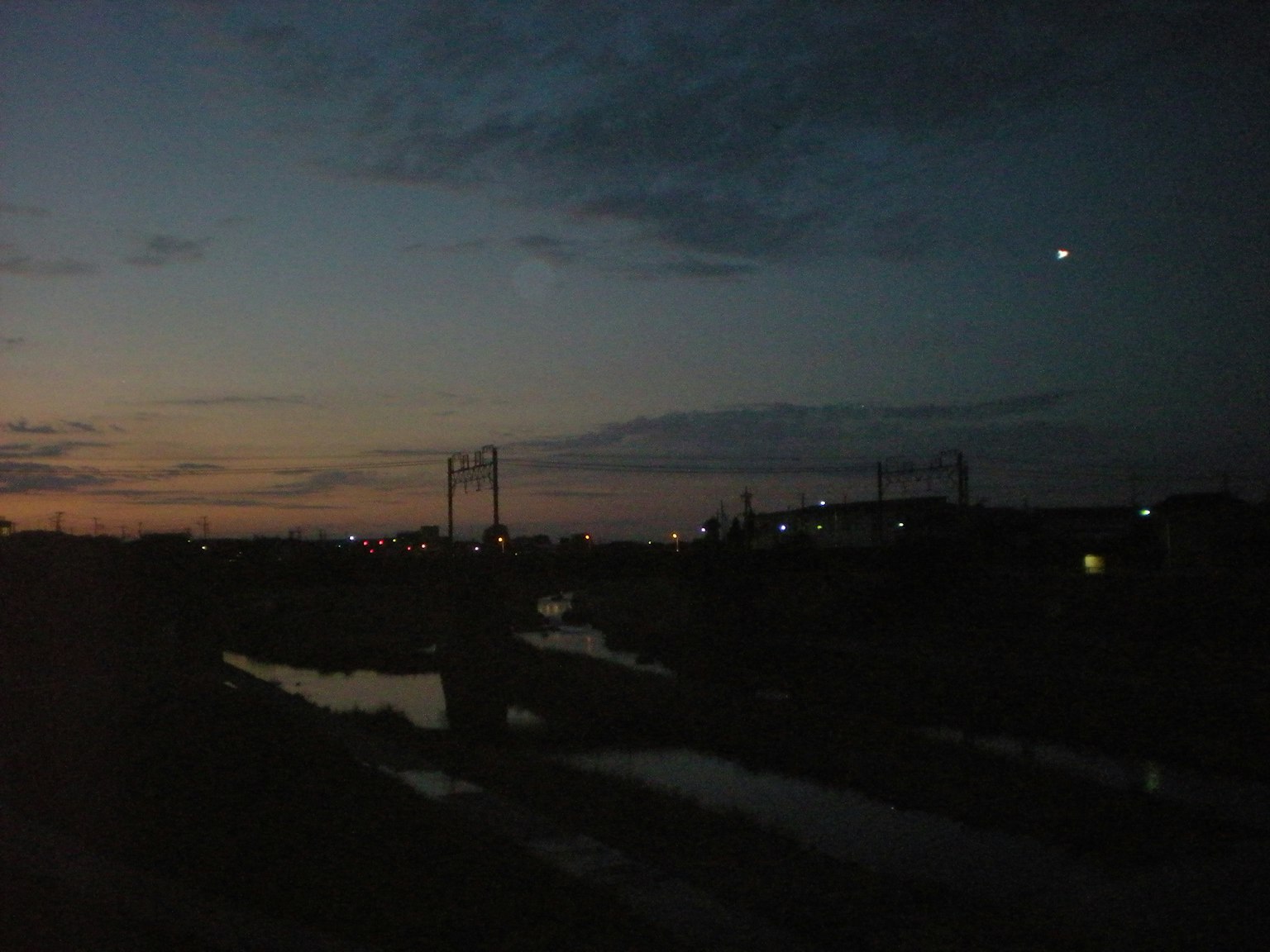 Twilight view of a river and bridge with distant city lights