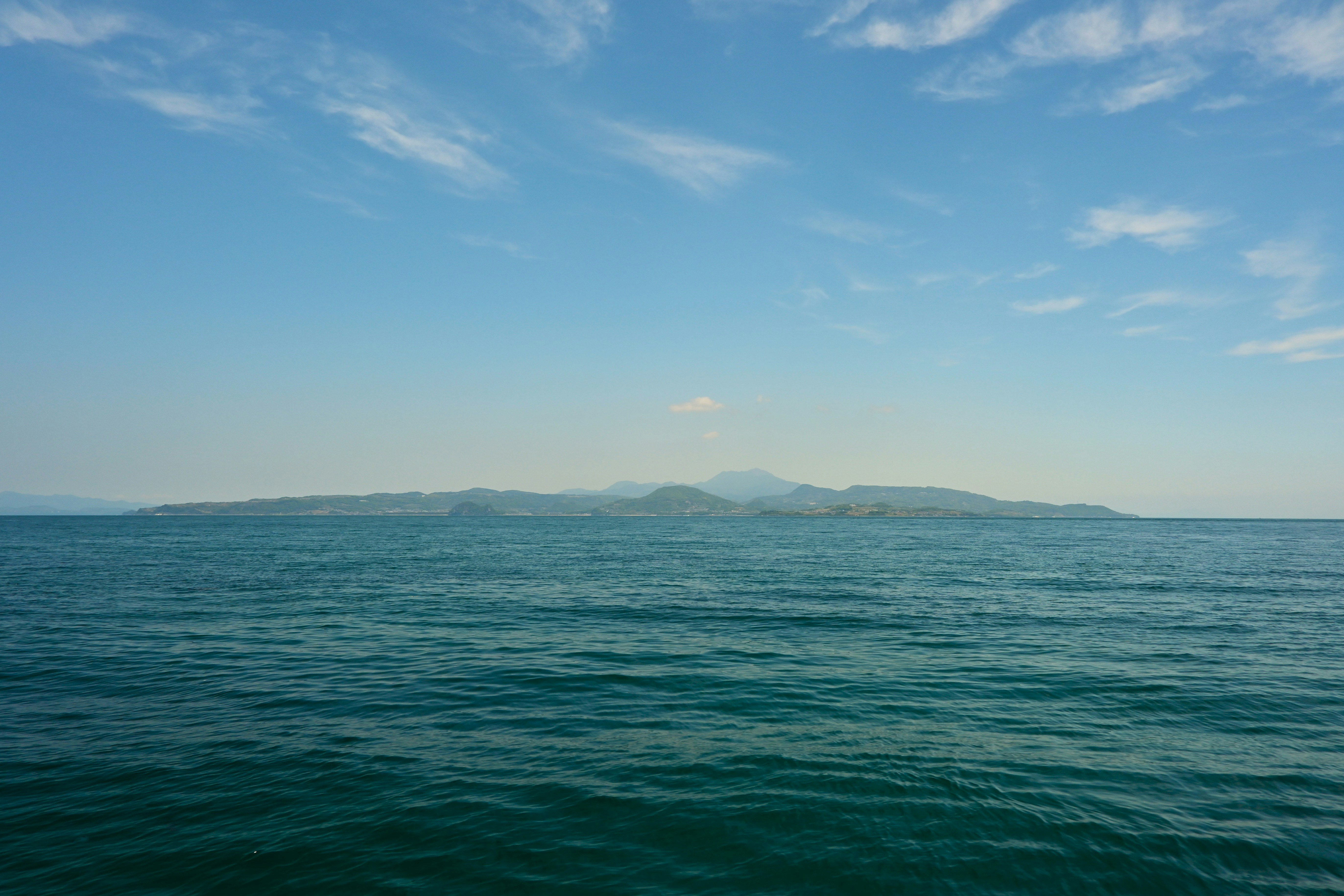 青空の下に広がる海と遠くの山並み