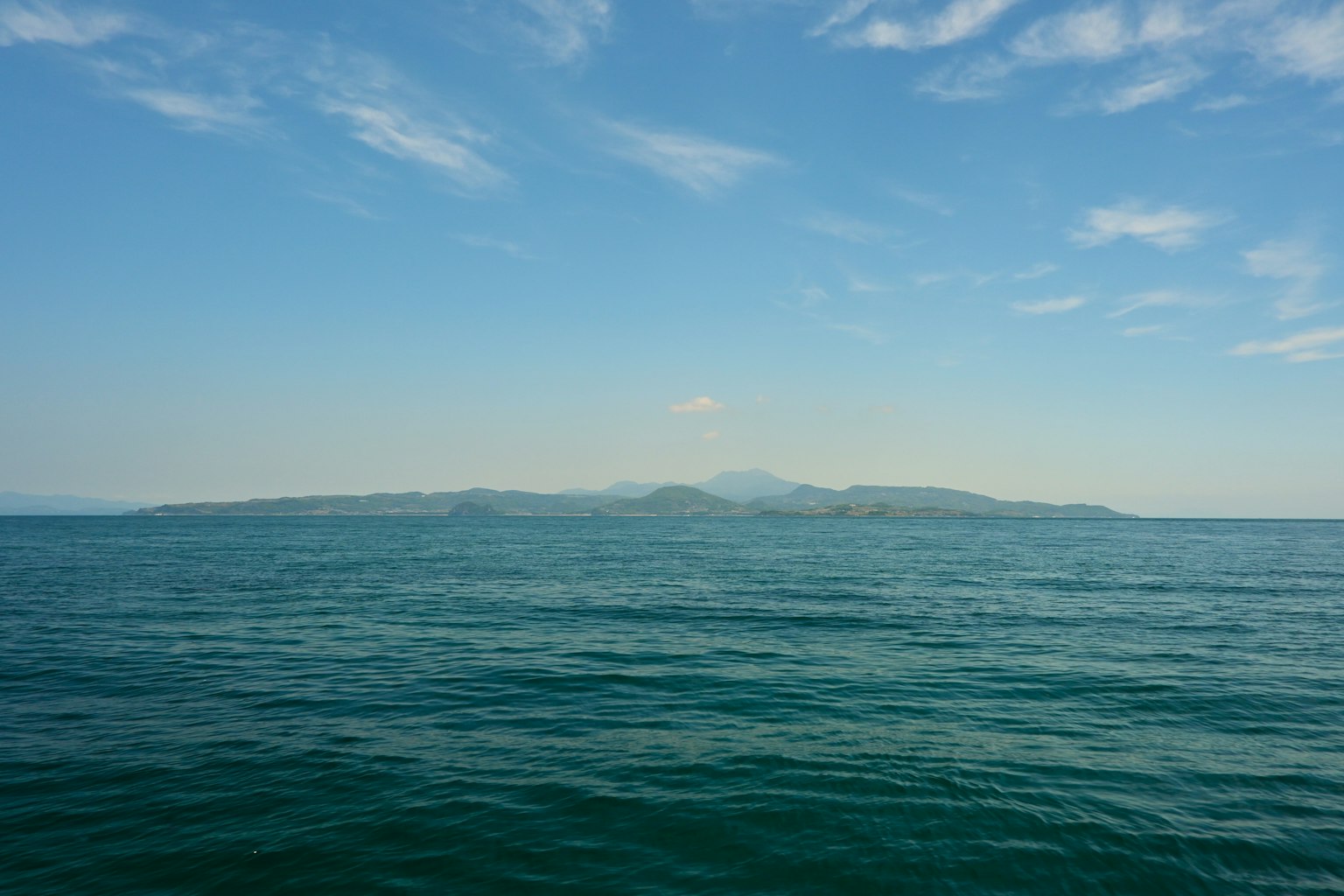Silhouette of an island on a blue sea and sky
