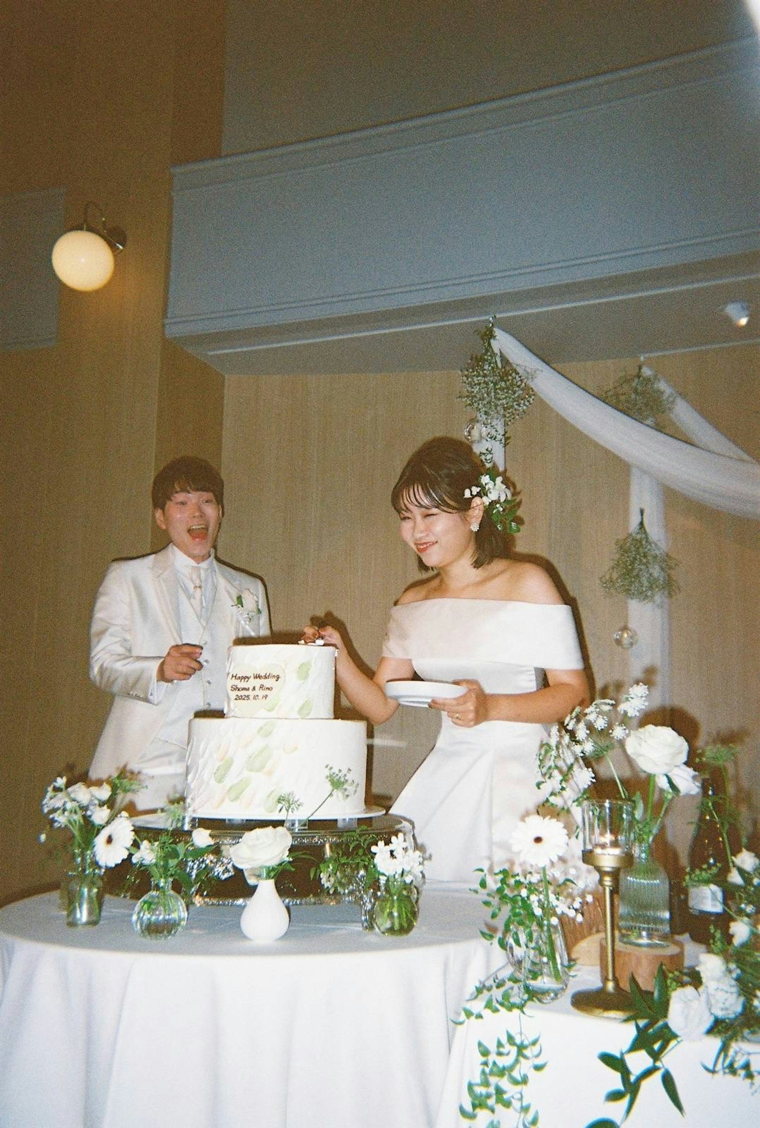 結婚式のケーキカットをする新郎新婦 白いドレスとタキシード 花の装飾が施されたテーブル