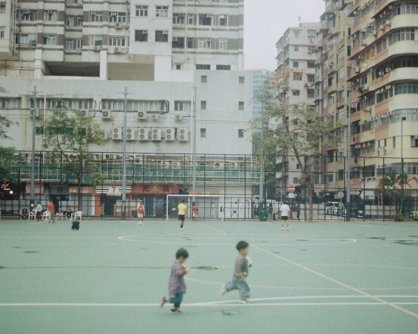 子供たちが緑のスポーツフィールドで遊んでいる様子 古い建物が背景にある