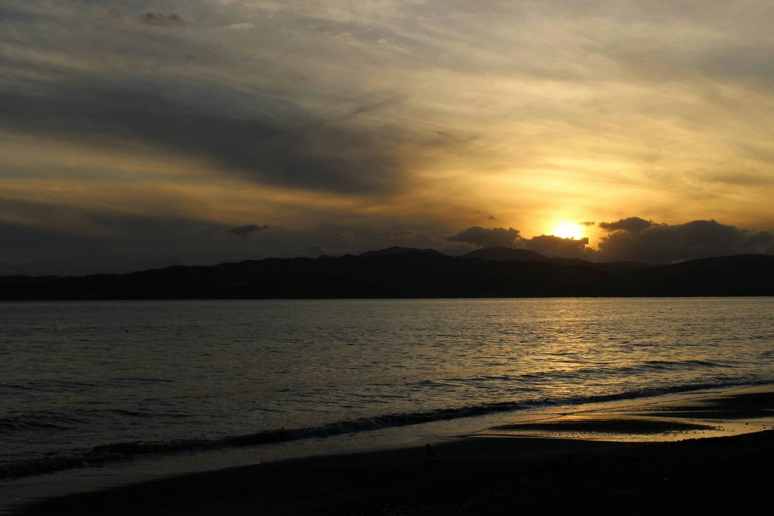 Sonnenuntergang an einem ruhigen Strand mit Wellen und Horizont