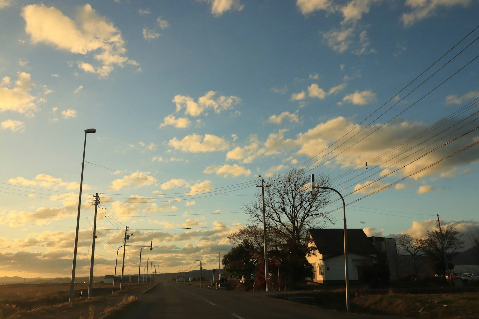 Scenic road at dusk with houses and beautiful clouds in the sky