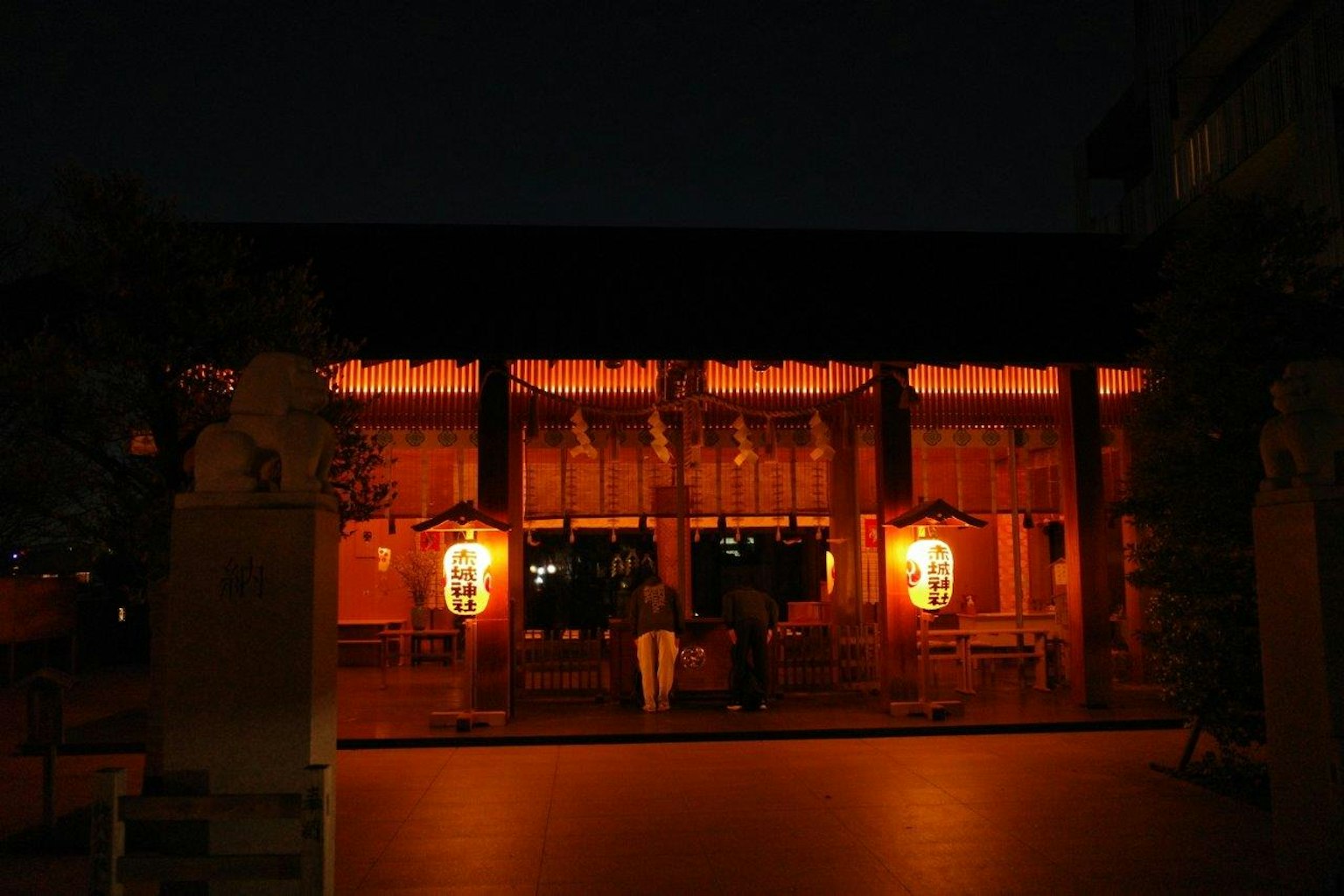 Esterno di un tempio di notte con lanterne rosse illuminate
