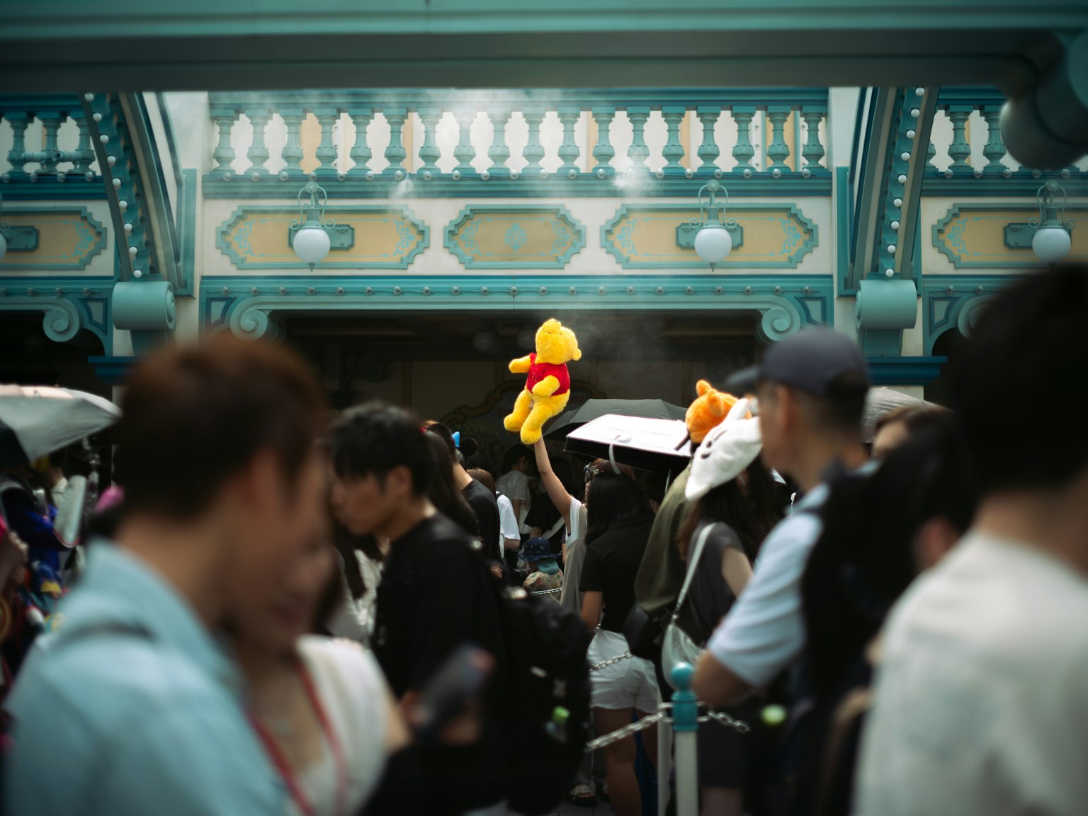 人々が集まる中で、黄色いクマのぬいぐるみを持つ人が目立つ風景