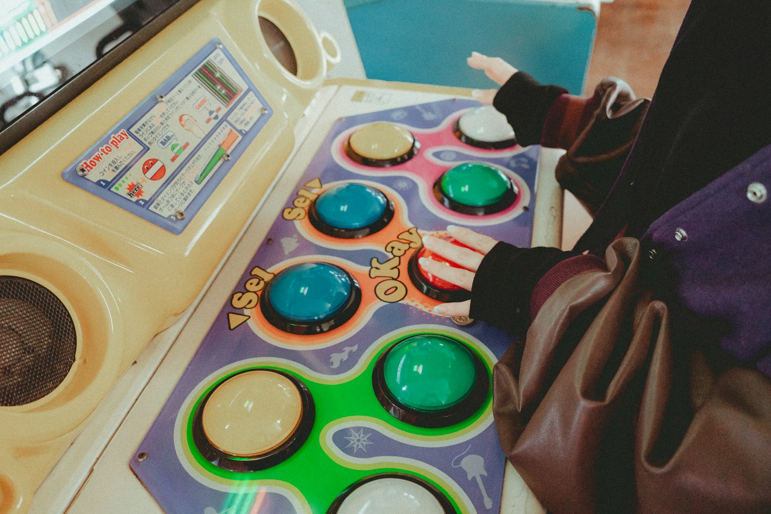 Main d'une personne reposant sur des boutons colorés d'un panneau de contrôle de jeu d'arcade
