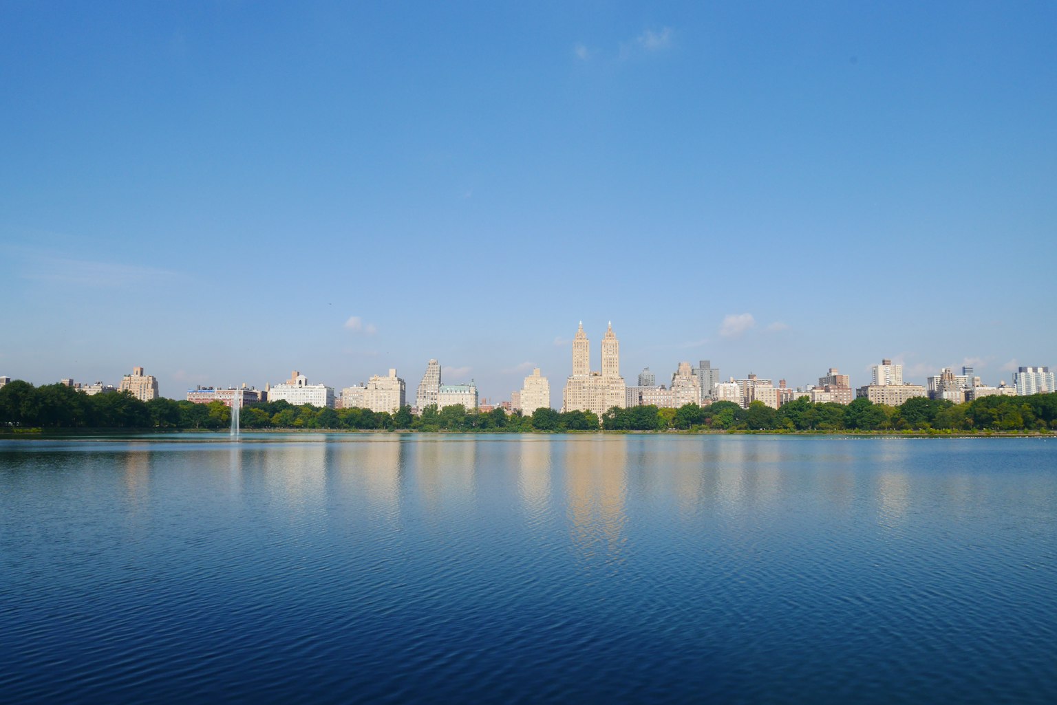Vue du lac de Central Park avec la silhouette de New York sous un ciel bleu clair