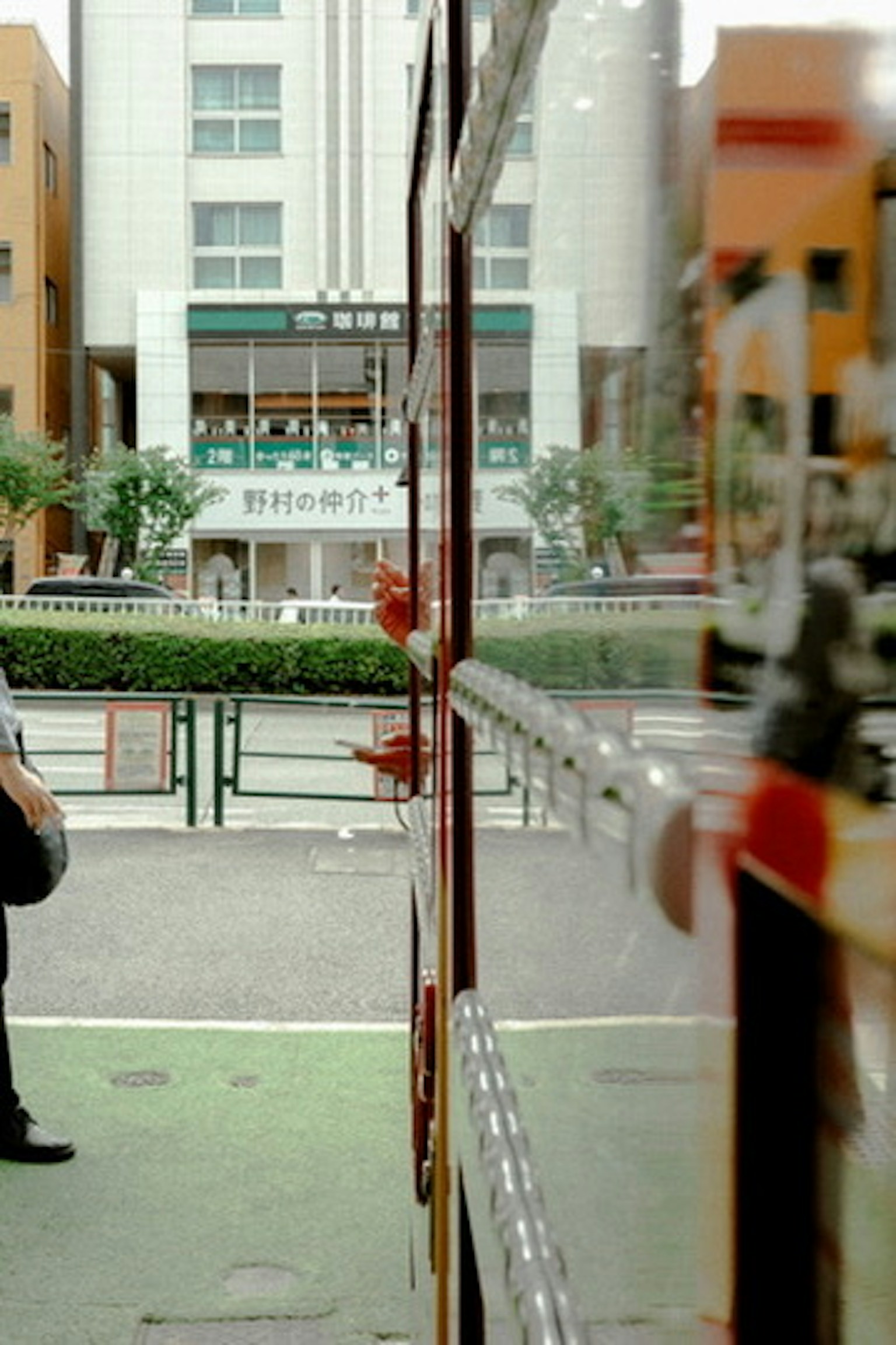 Pemandangan sebuah halte bus dengan seseorang yang menunggu dan bangunan di latar belakang