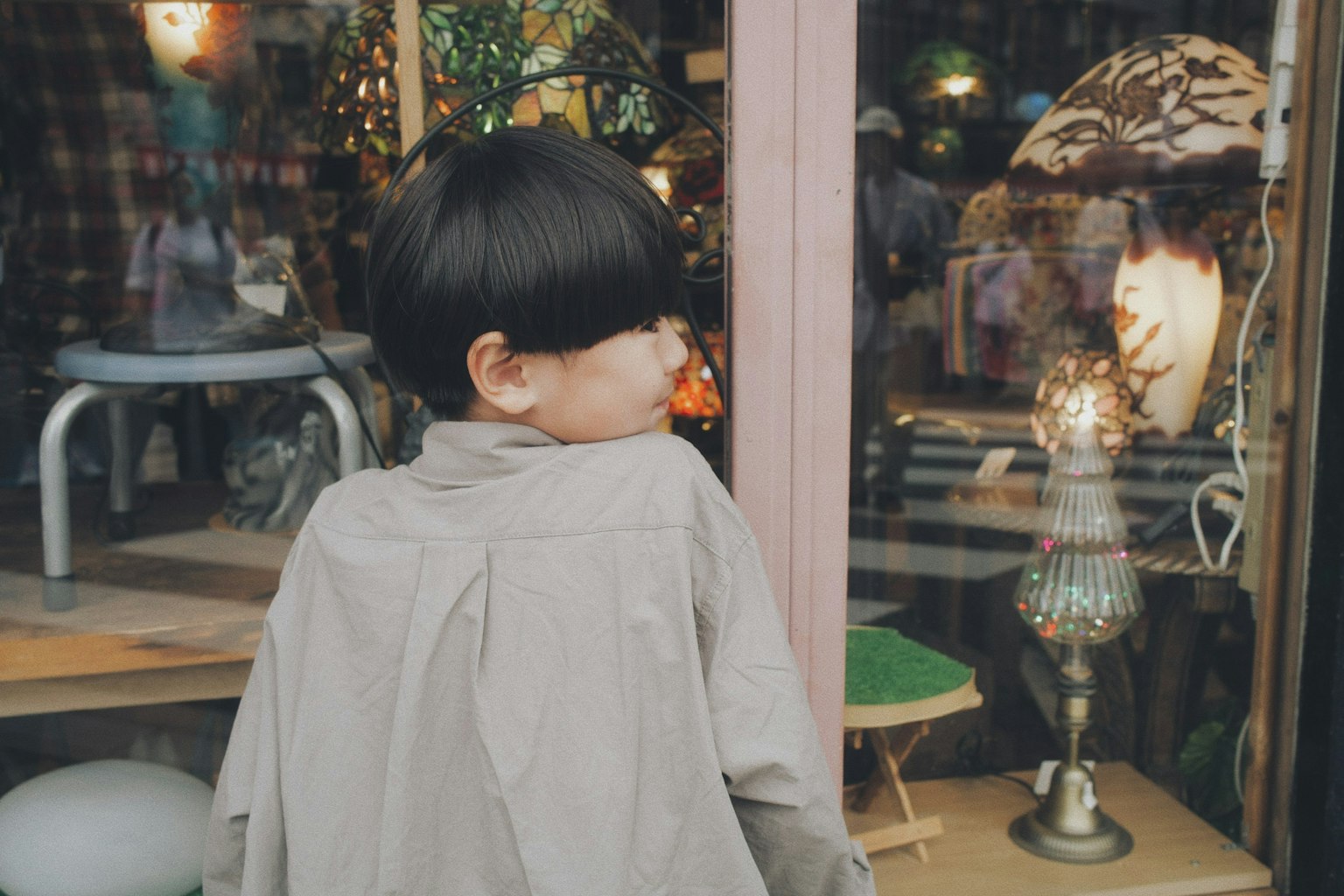 子供が店の前で振り返っている様子 背景には装飾品や家具が見える