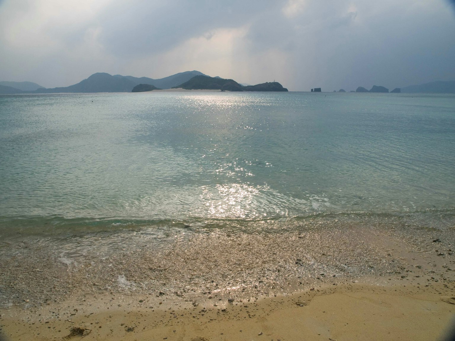 宁静的海滩景观，轻柔的波浪和遥远的岛屿