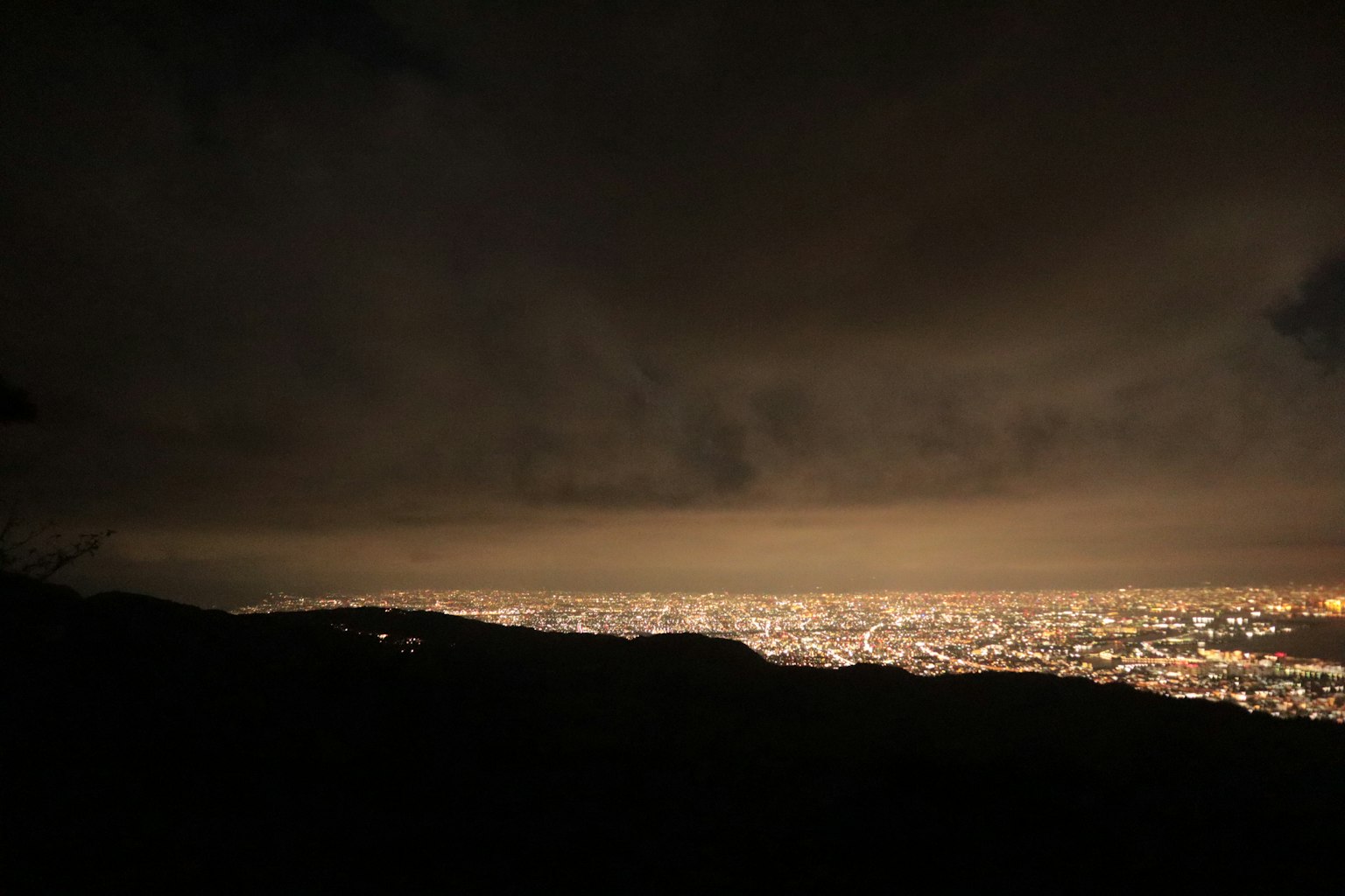 夜景城市灯光延伸至地平线黑暗的天空和山的轮廓