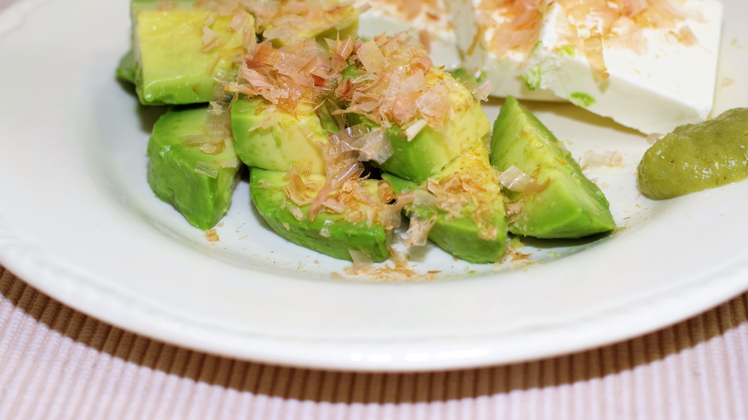 Piatto di fette di avocado guarnite con scaglie di bonito e tofu