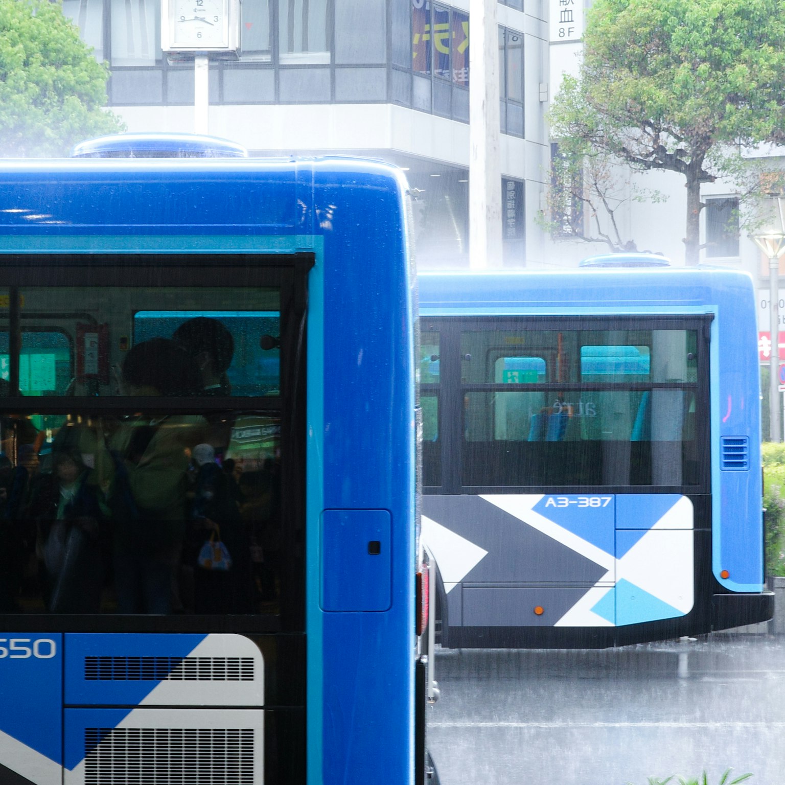 Buses azules en un entorno urbano bajo la lluvia