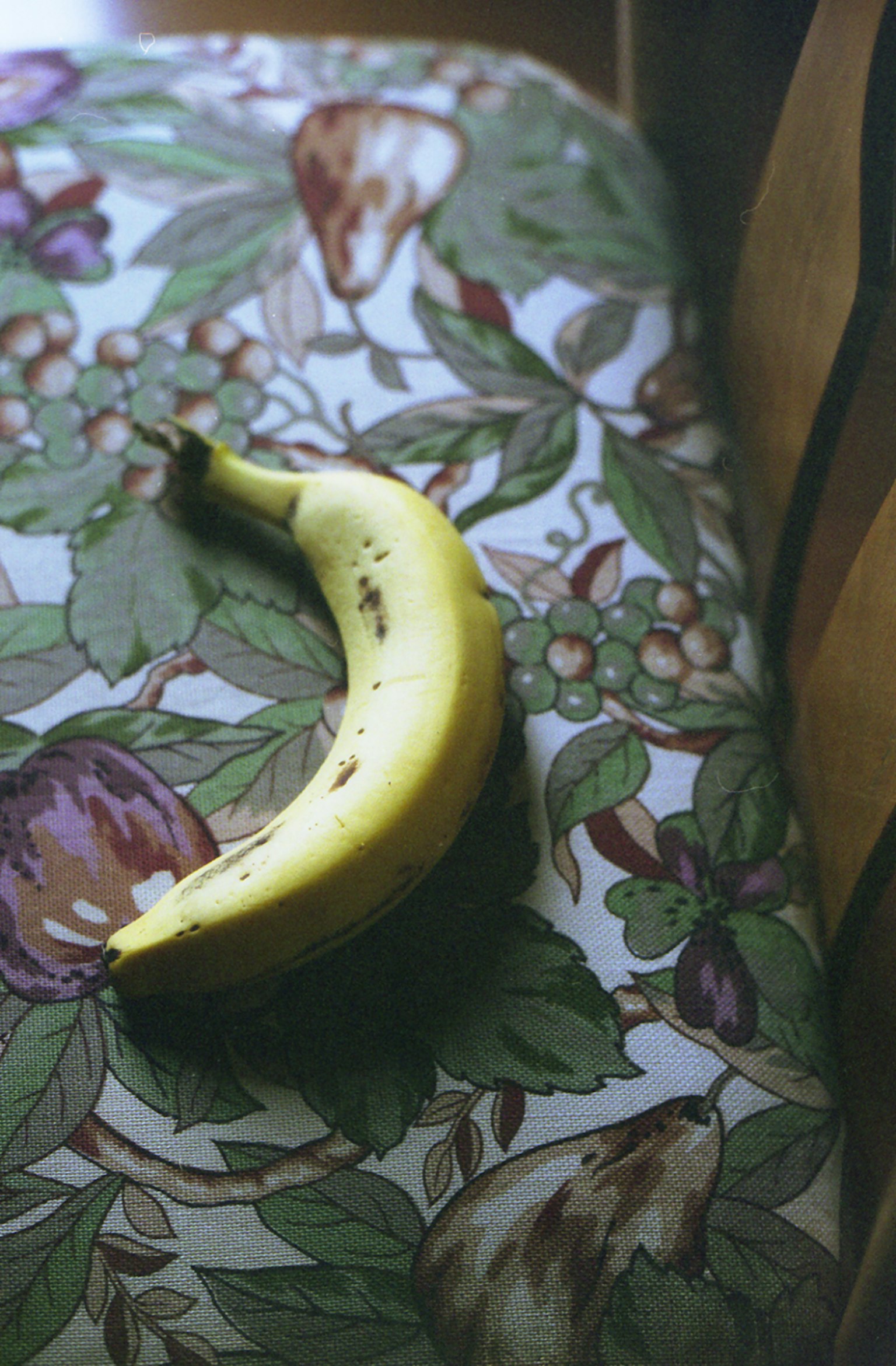 Yellow banana resting on a floral patterned tablecloth