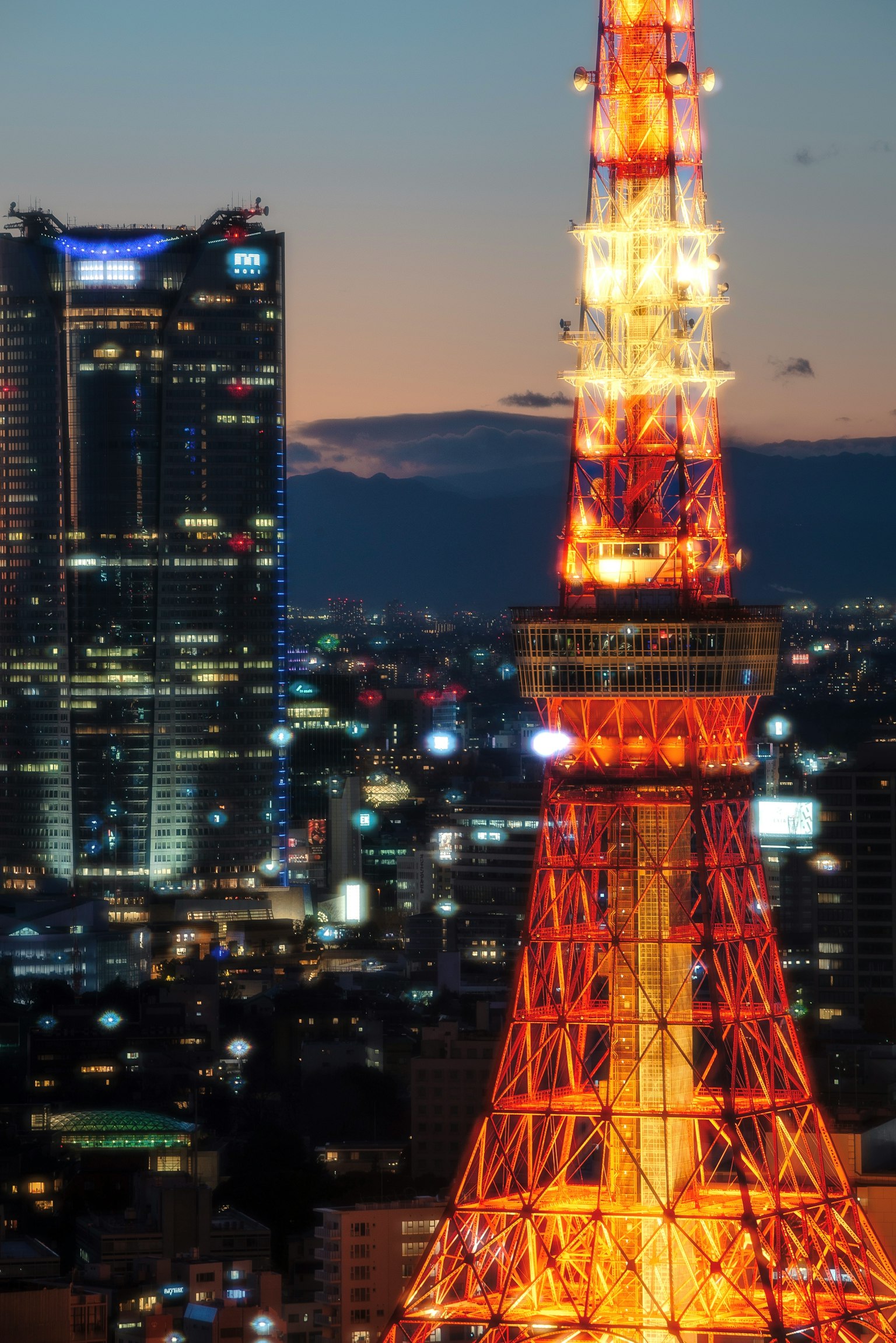 Torre de Tokio de noche con luces naranjas iluminadas rascacielos de fondo