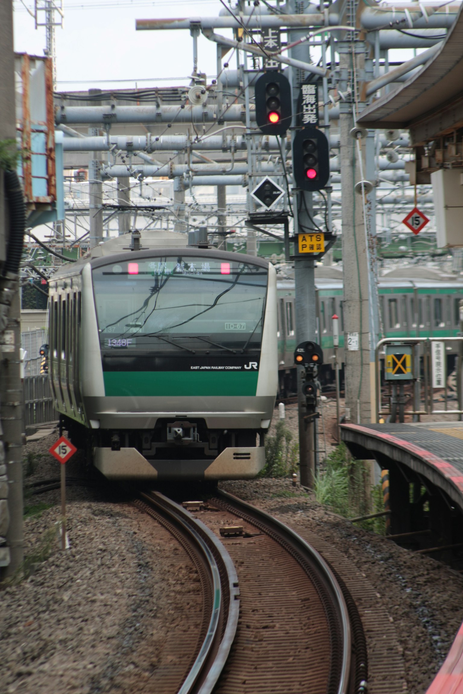 Ein grüner Zug, der auf gebogenen Gleisen fährt, mit roten Signalen beleuchtet