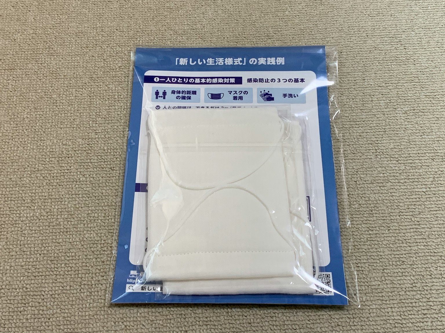 Un produit de masque blanc emballé avec une étiquette en fond bleu comportant un texte en japonais