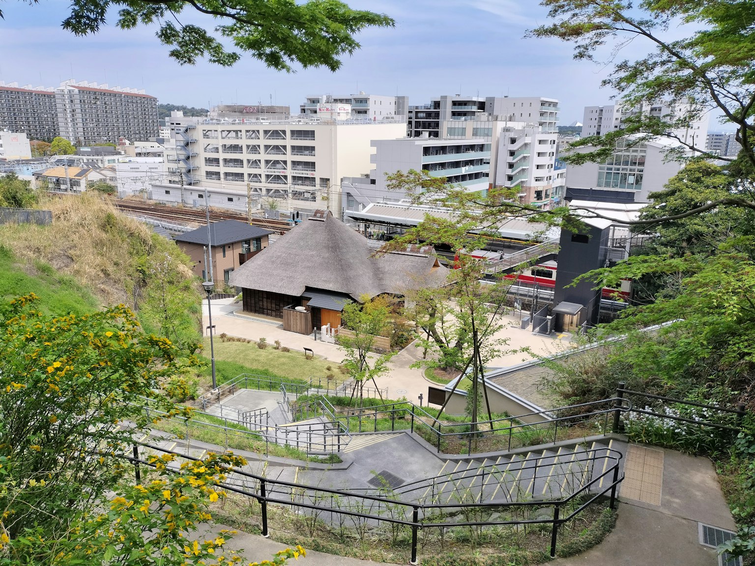Sebuah rumah tradisional Jepang dikelilingi oleh pepohonan dan bangunan modern