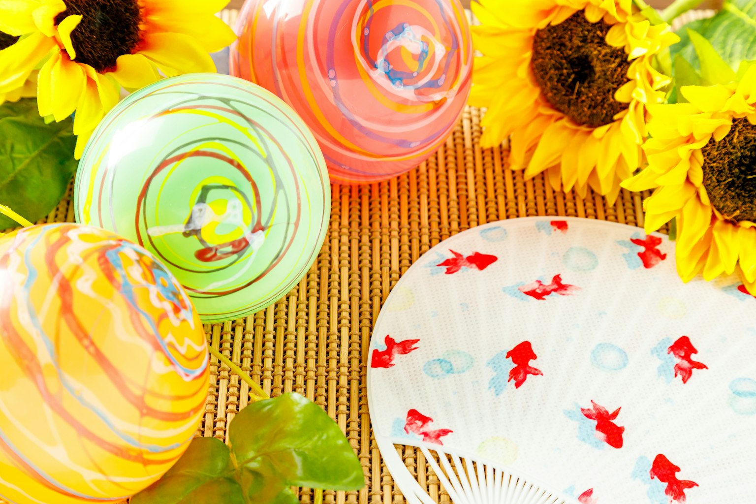 Bonbons ronds colorés avec des motifs et un éventail avec des motifs de poissons rouges près de tournesols